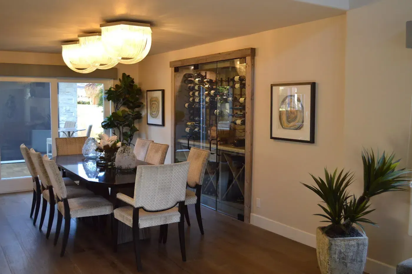 Modern dining room with dark wood table, upholstered chairs, pendant light, and a glass cabinet