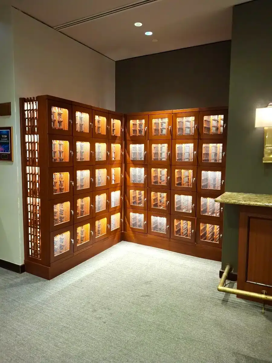Illuminated wooden wall of photo display cases in a hallway corner, with carpeted floor and ceiling lights