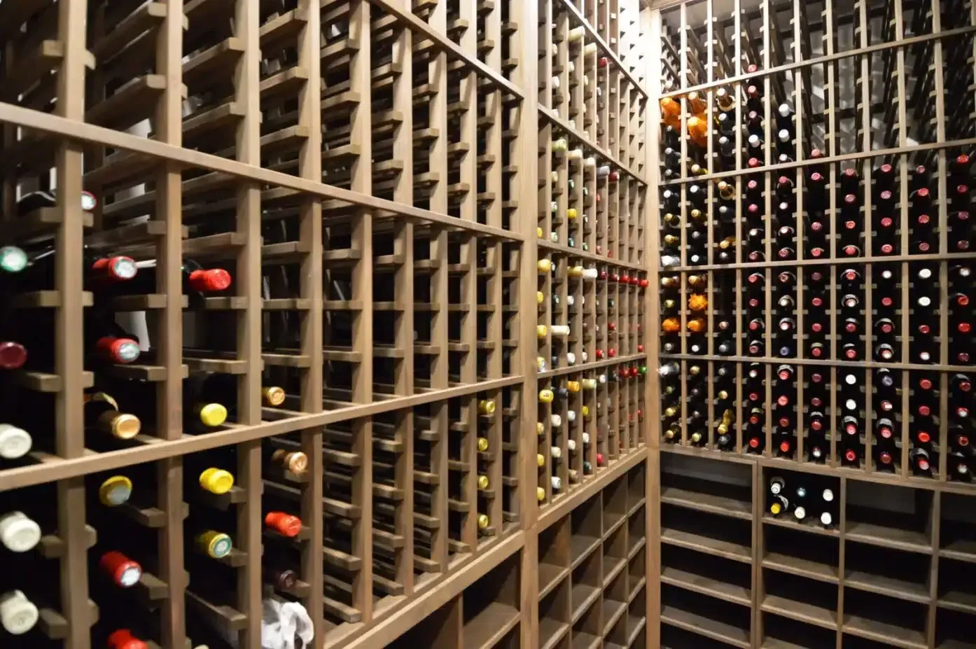 Rows of wine bottles stored in a wooden wine cellar rack