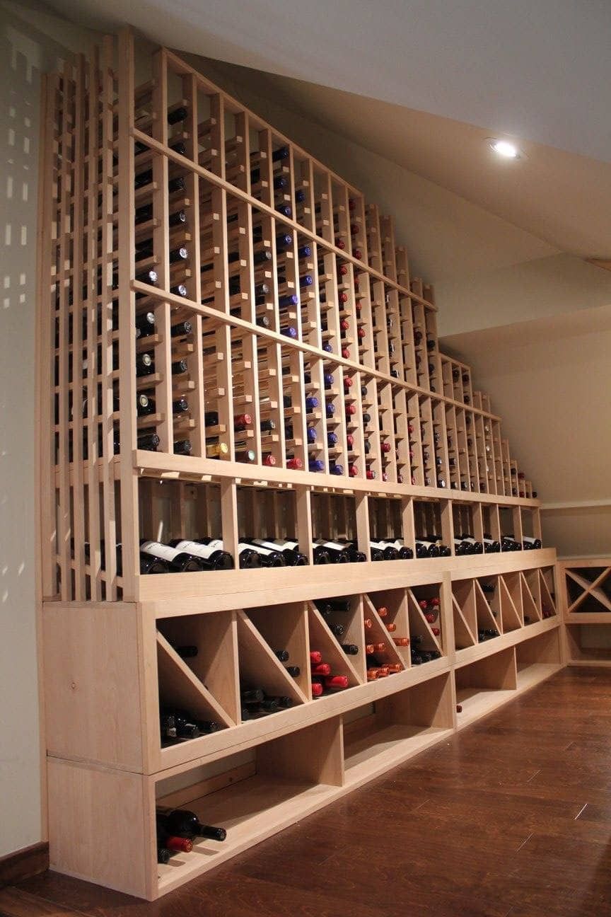 Wall-mounted wine rack with rows of bottles in a warmly lit cellar-like room
