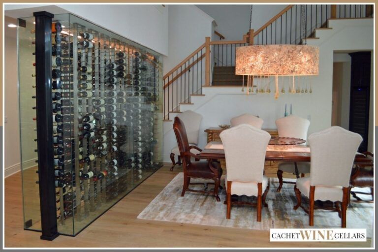 Modern dining room with glass wine wall, round table, and staircase in the background