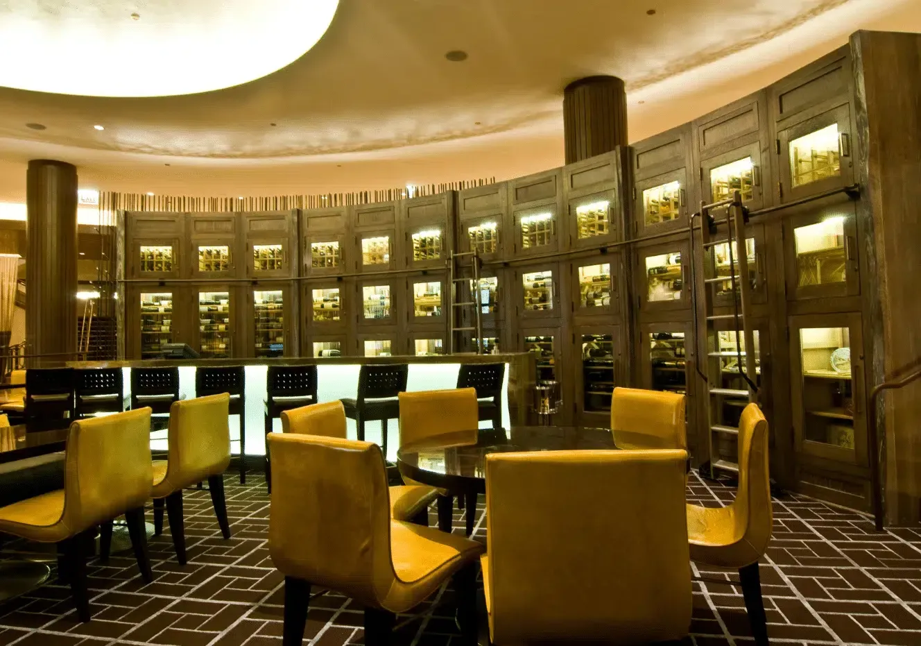 Elegant library lounge with yellow chairs, bookshelves, and warm ambient lighting