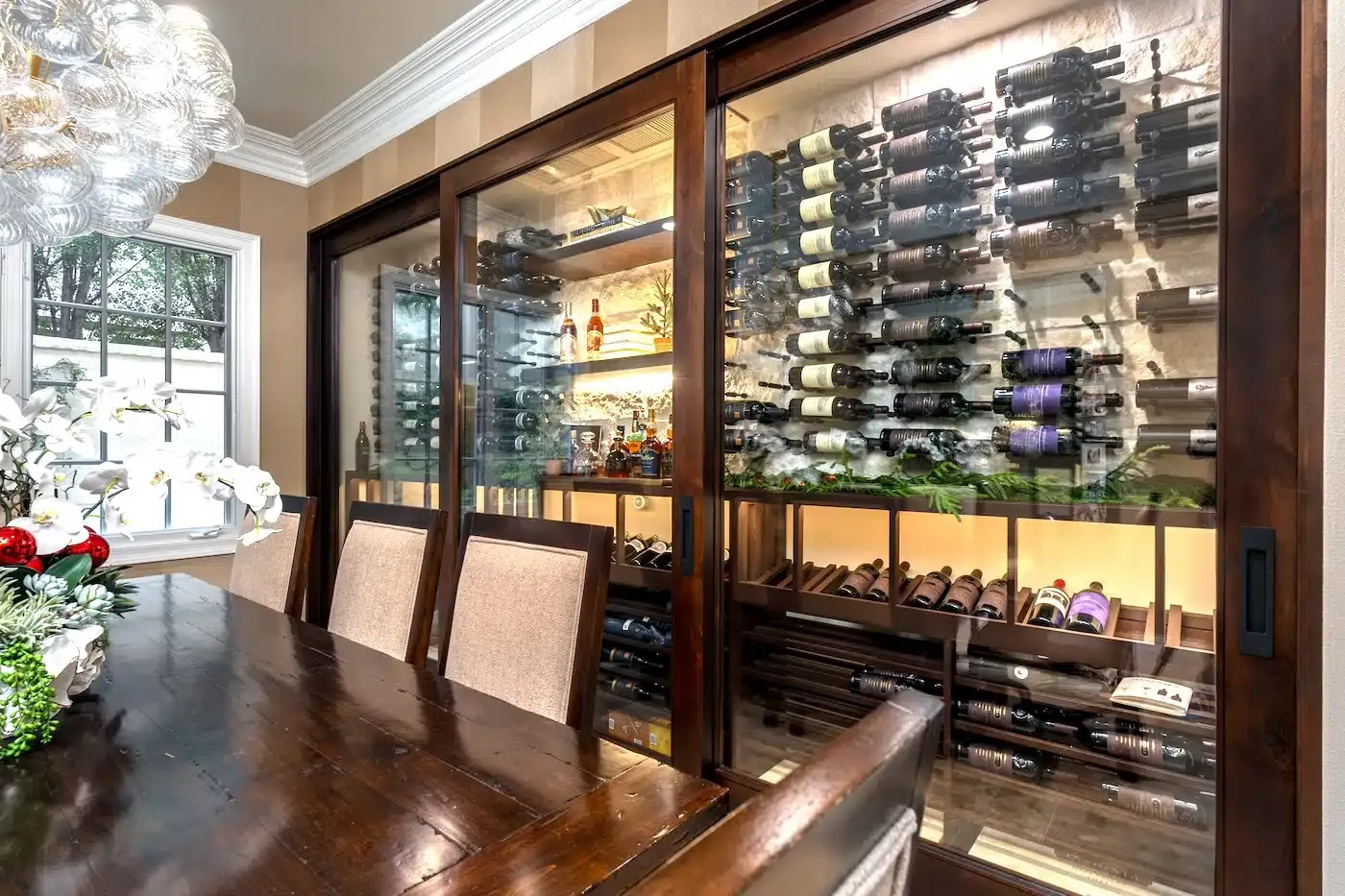 Dining room with glass wine cabinets filled with bottles beside a wooden table and chairs