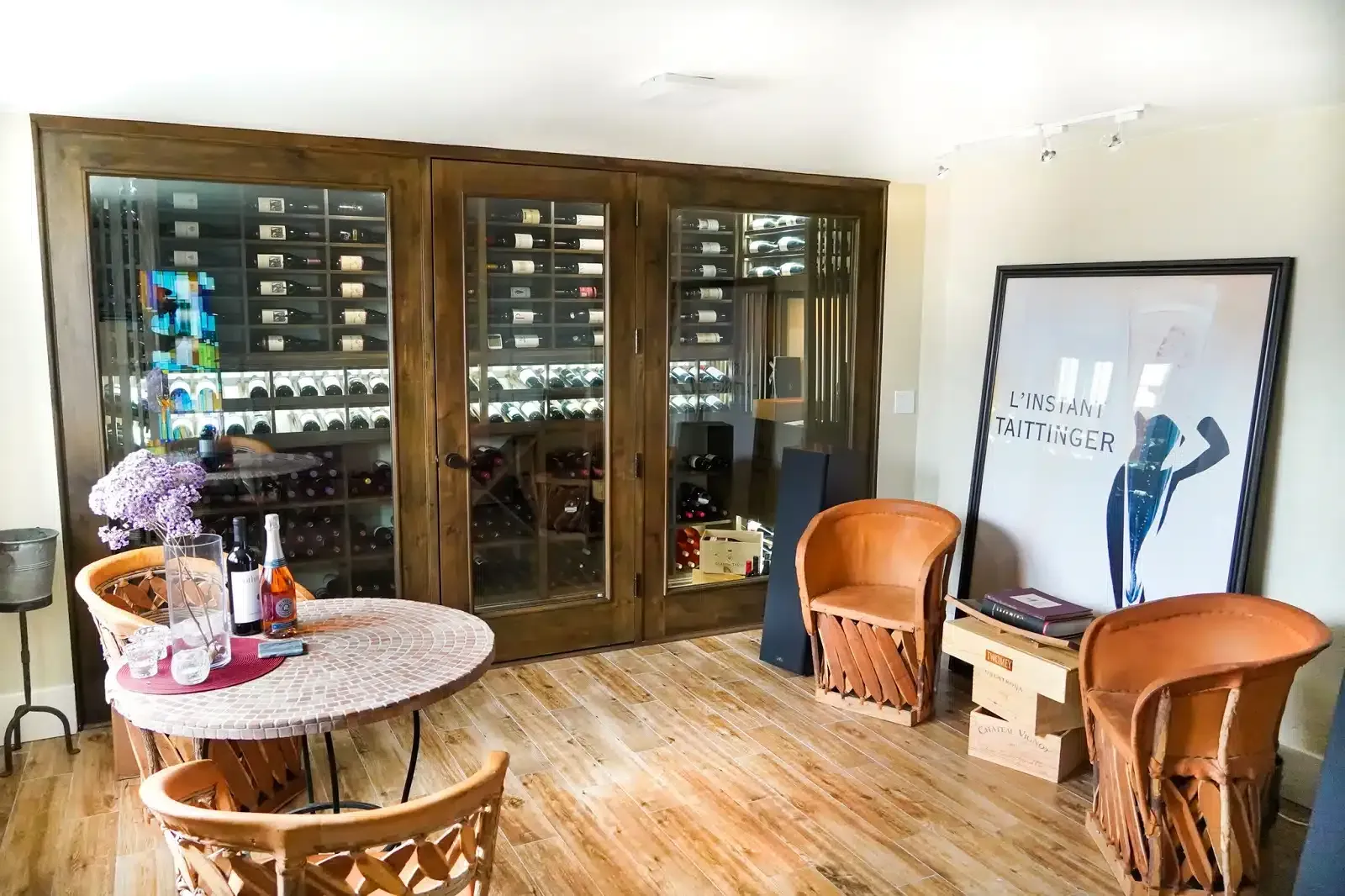 Living room with a round table, wicker chairs, wood floors, and a large framed artwork on the wall
