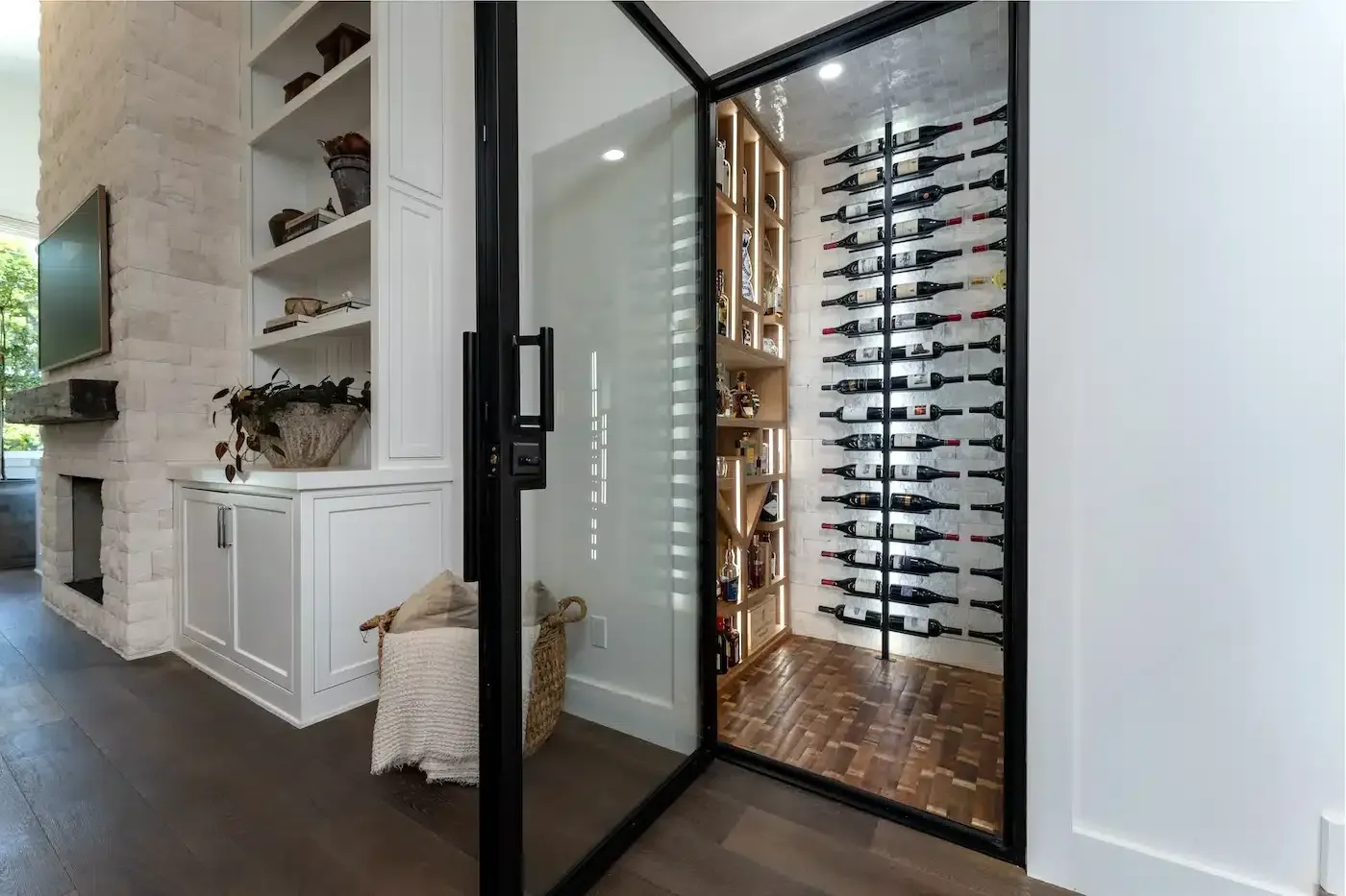 Modern home wine room with glass door, floor-to-ceiling racks, and white built-in cabinetry