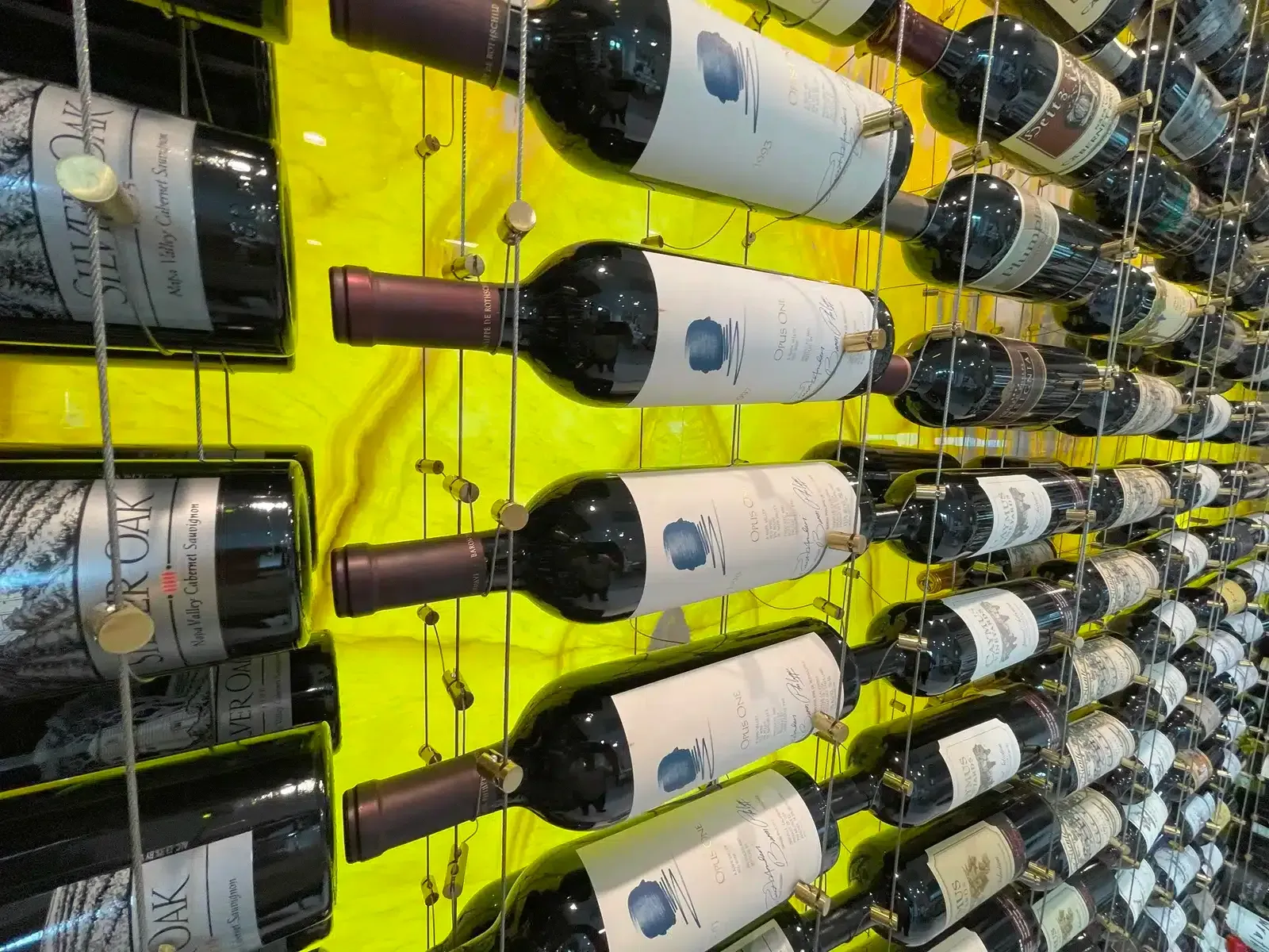 Rows of wine bottles stored horizontally on a bright yellow wall rack