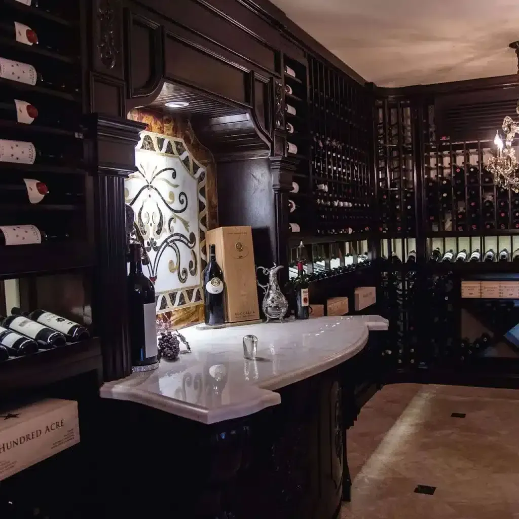 Dimly lit elegant wine cellar bar with curved white counter, dark wood, and wine bottles lining the walls