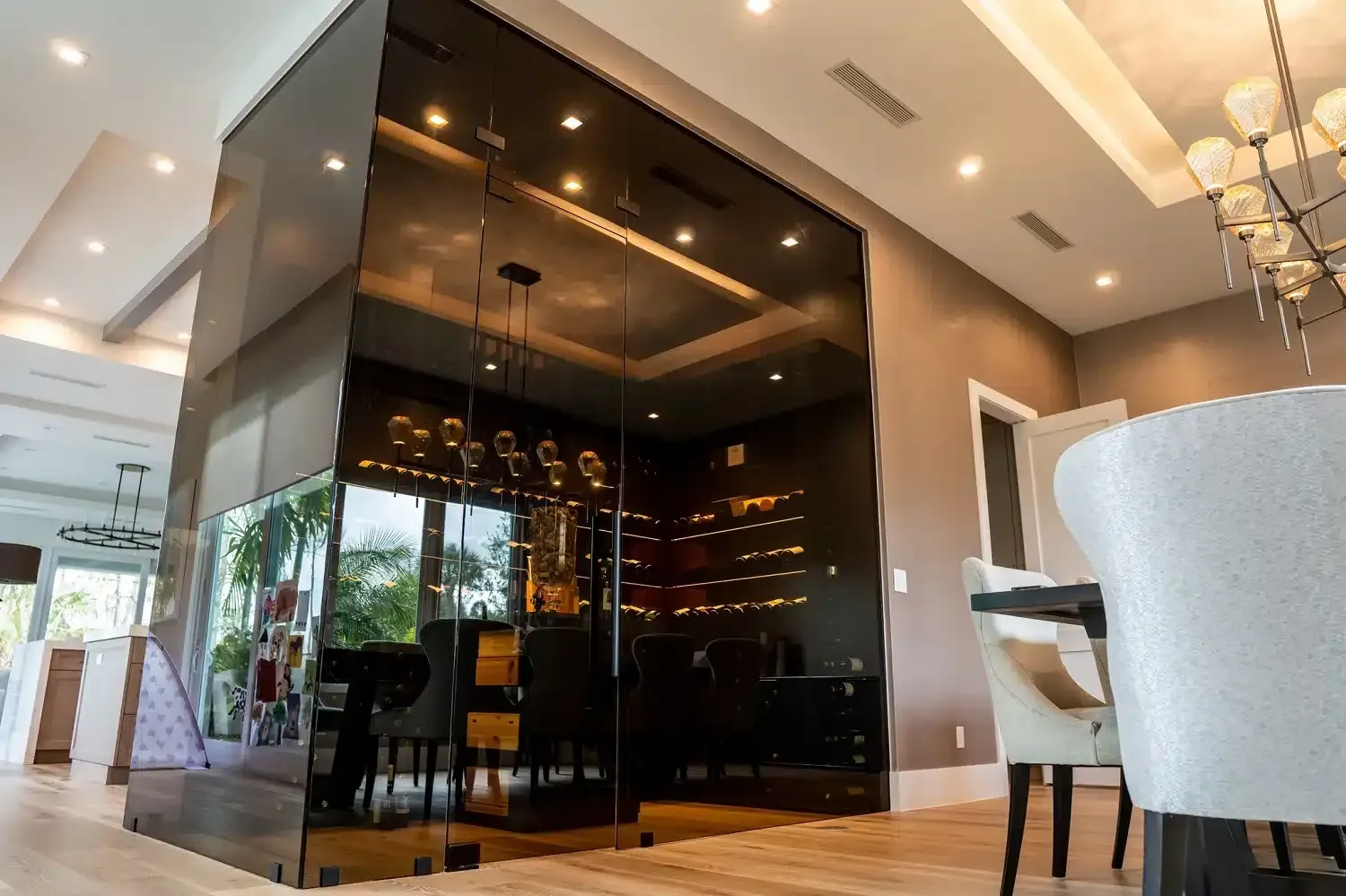 Modern restaurant interior with dark glass partition, warm pendant lights, and white chairs