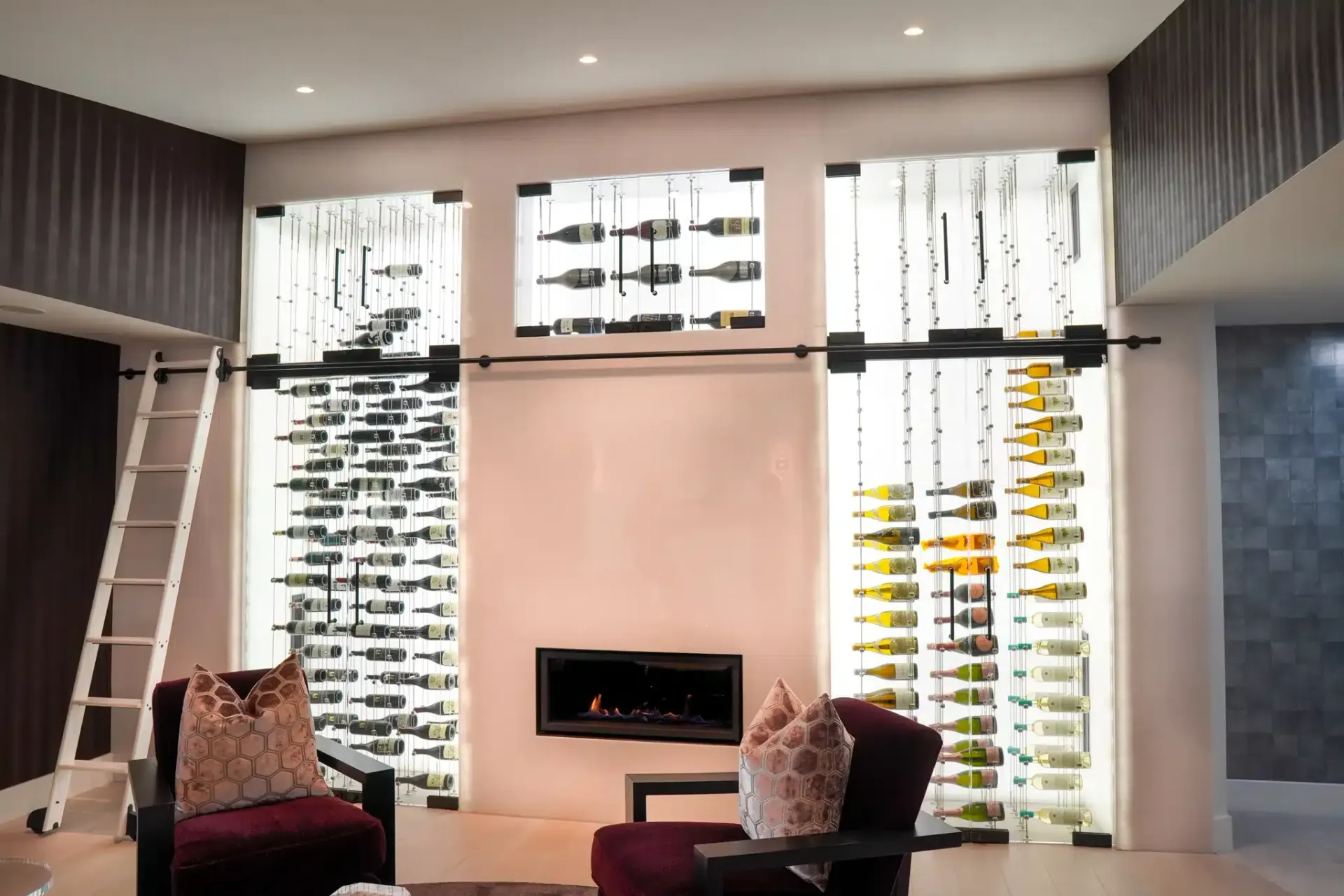 Modern living room with tall windows, pink accent wall, fireplace, and two chairs facing inward