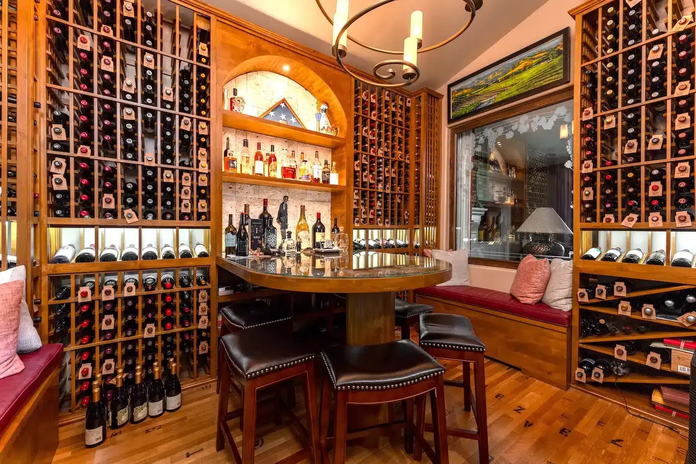 Cozy wine cellar with floor-to-ceiling racks, wooden table and chairs, and warm amber lighting