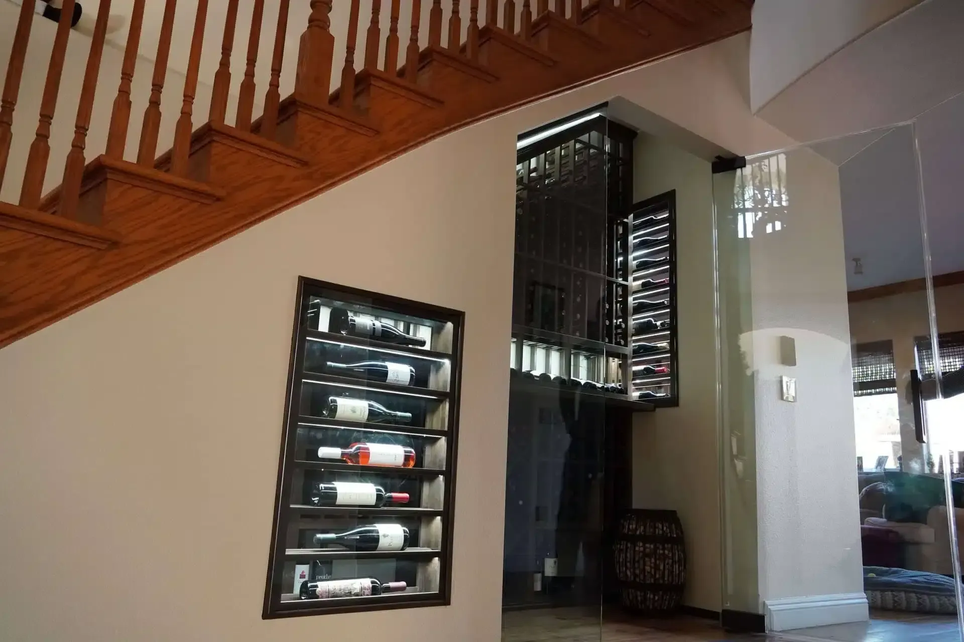 Staircase with wooden railings, wall wine rack, and a mirrored doorway in a modern home interior