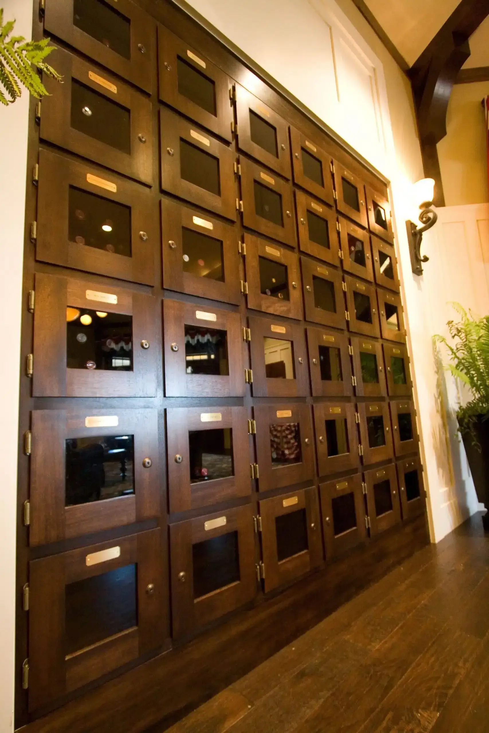 Wooden wall of square mail or locker compartments in a warmly lit interior lobby