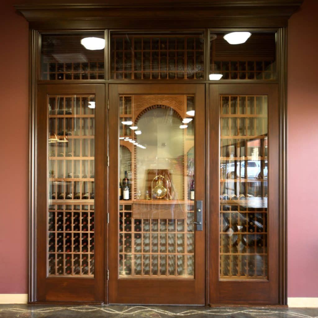Wooden wine cellar doors with glass panes and shelves of wine bottles inside