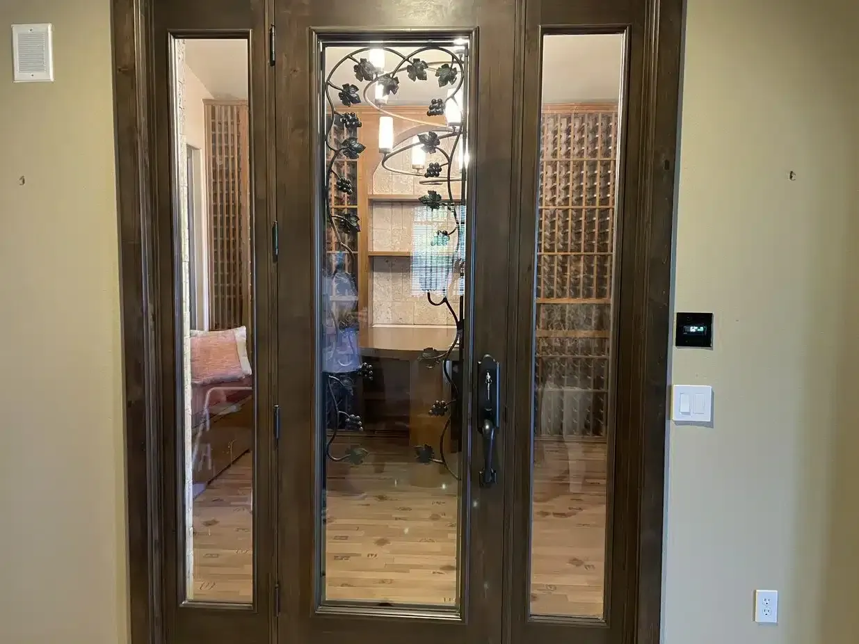 Wooden French doors with glass panels opening into a dining room with a chandelier.