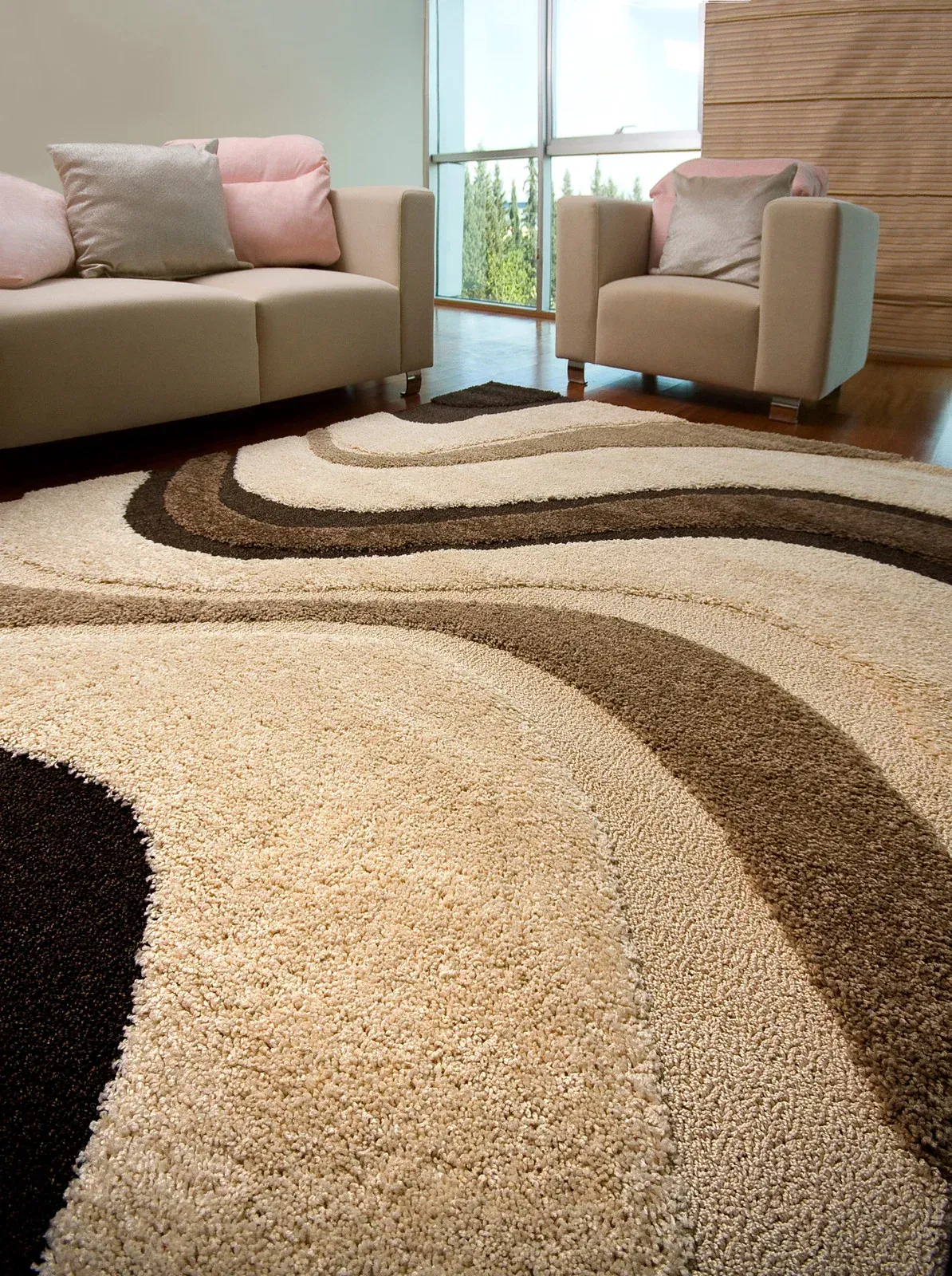 Beige and brown swirl rug in living room with a couch and armchair.