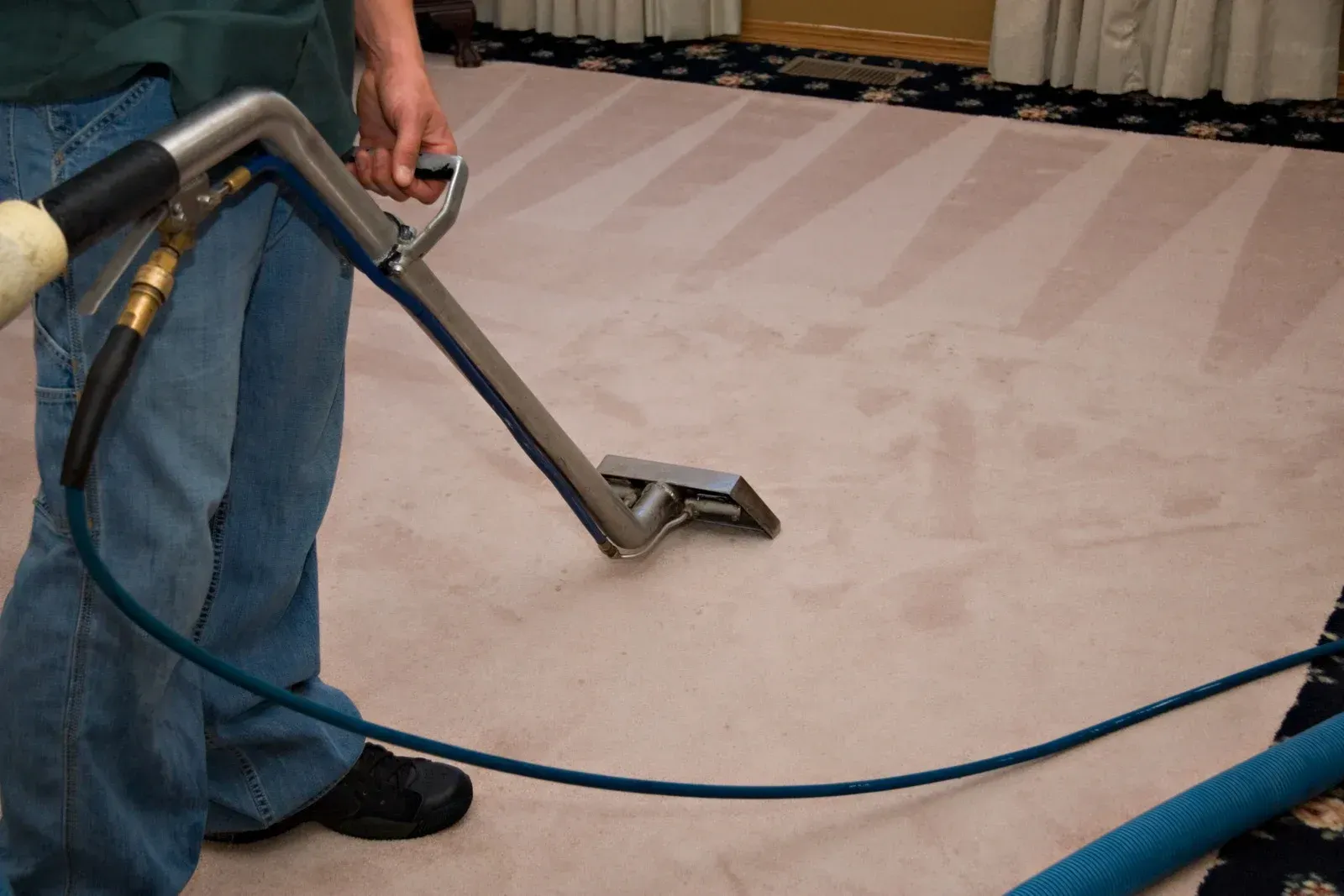 A man is cleaning a carpet with a vacuum cleaner