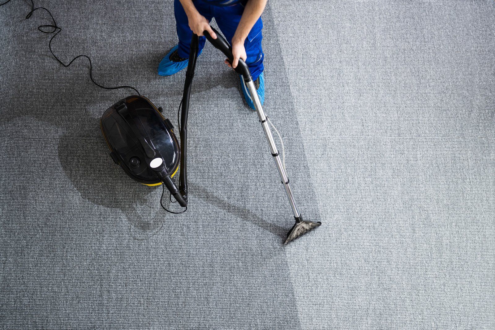 A person is using a vacuum cleaner to clean a carpet.