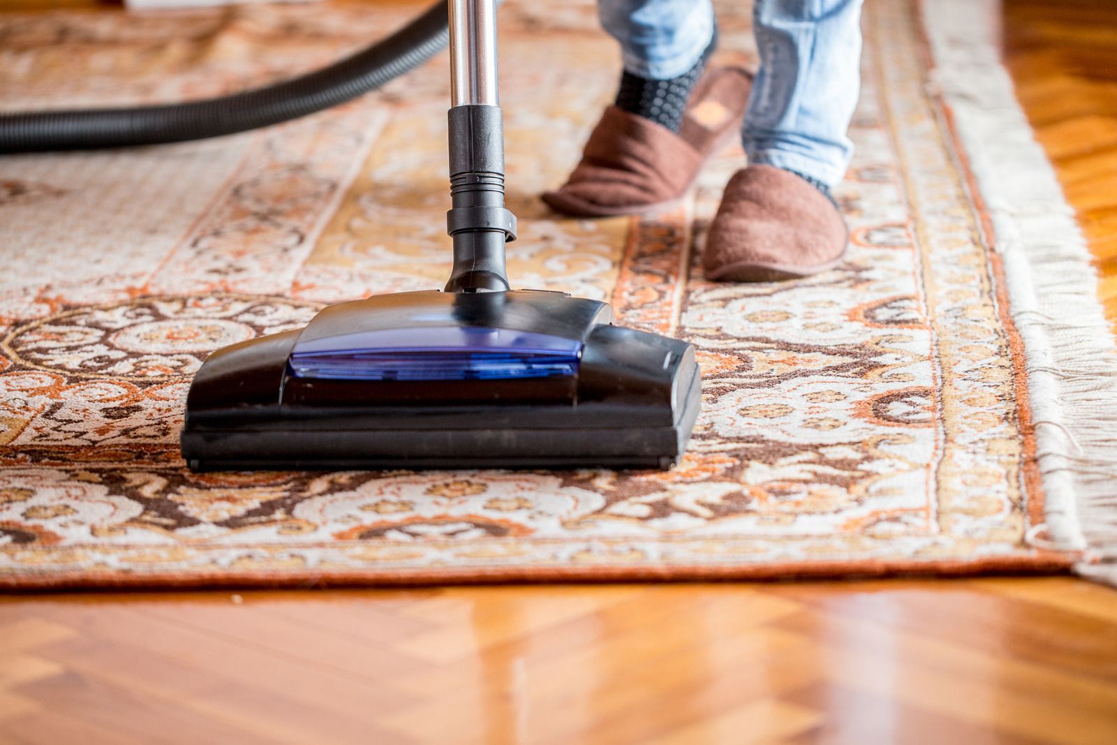 A person is using a vacuum cleaner to clean a rug.