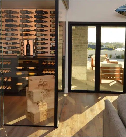 Wine display beside sliding glass doors opening to a sunny patio and waterfront view
