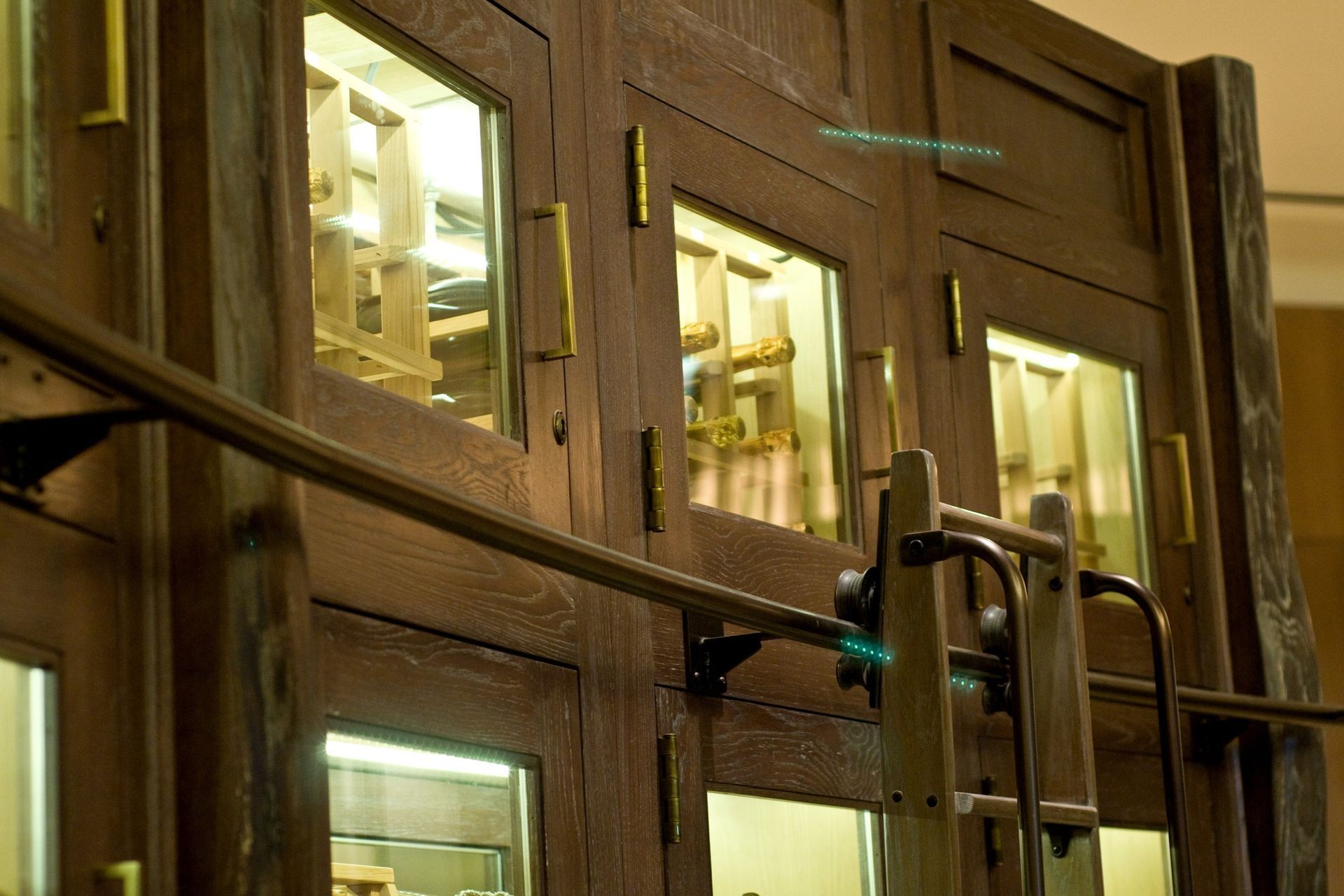 Close-up of wooden double doors with glass panes and metal handles in a warm-lit interior