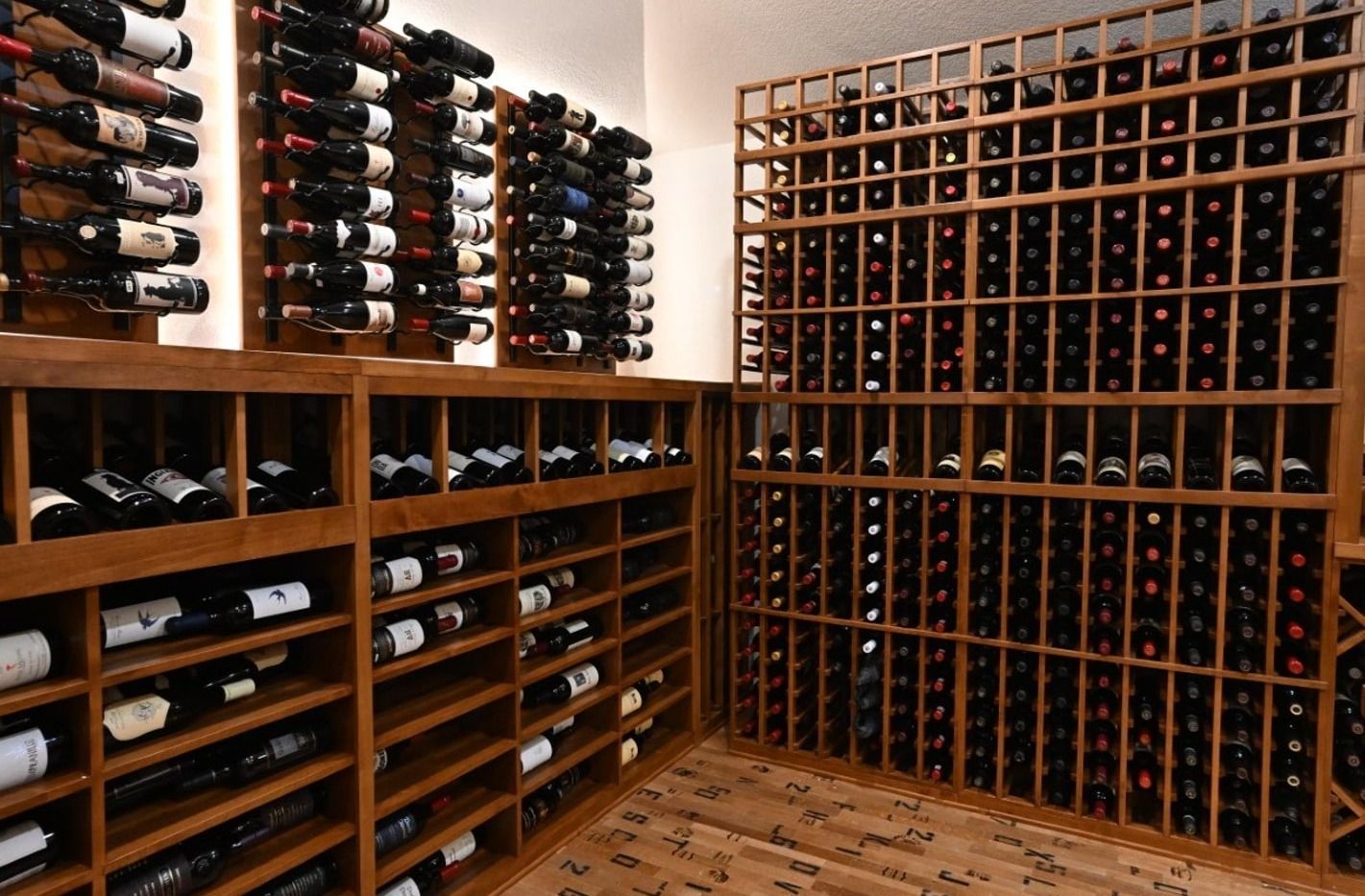 Wine cellar with wooden racks filled with bottles and a wooden floor