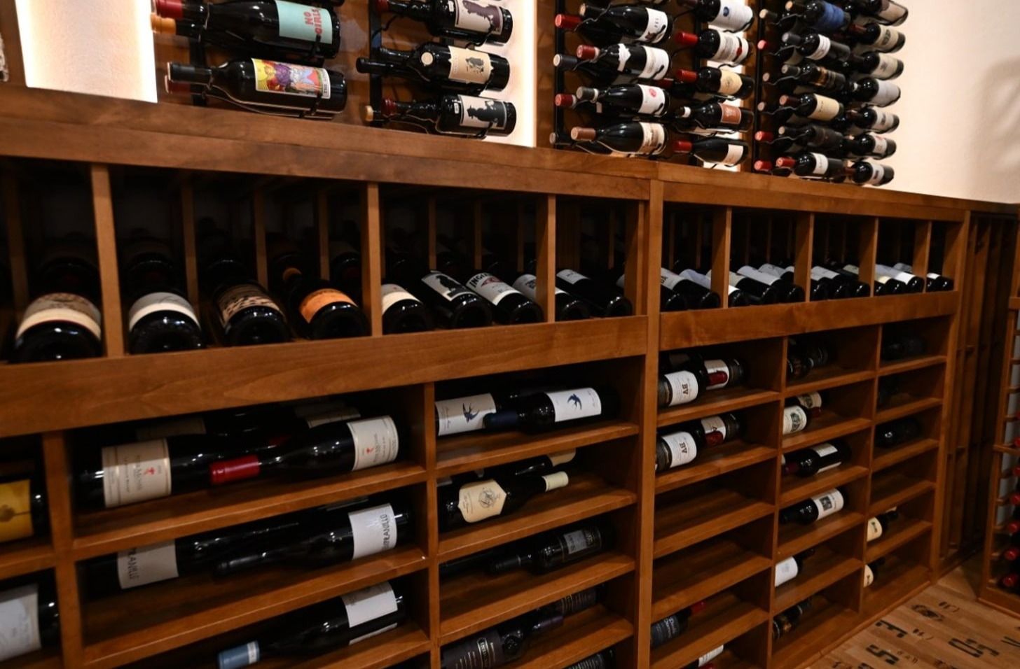 Wooden wine rack filled with assorted wine bottles in a cellar-style room