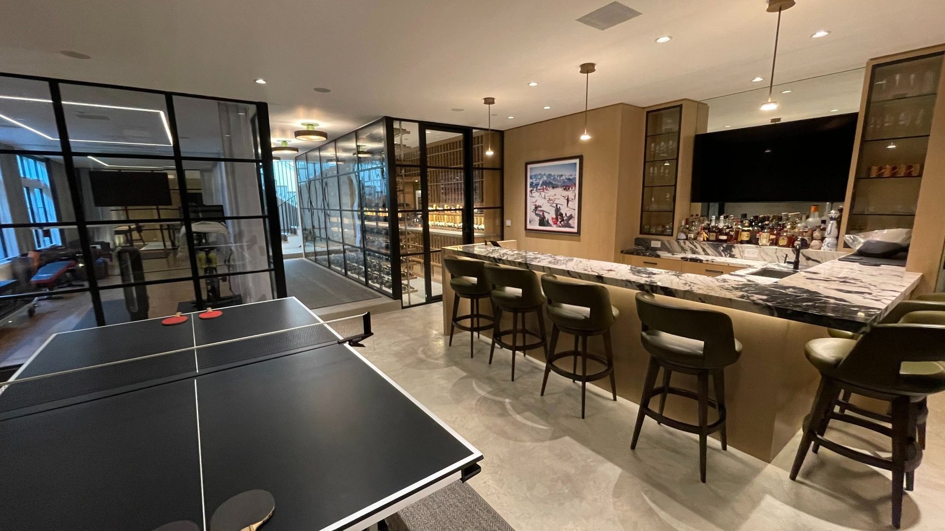 Modern bar lounge with pool table, stools, and a ping-pong table in a sleek indoor entertainment space