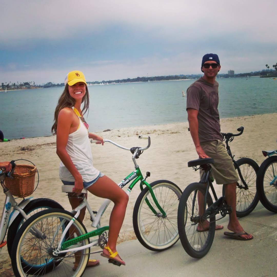 a man and a woman are standing next to bicycles on the beach