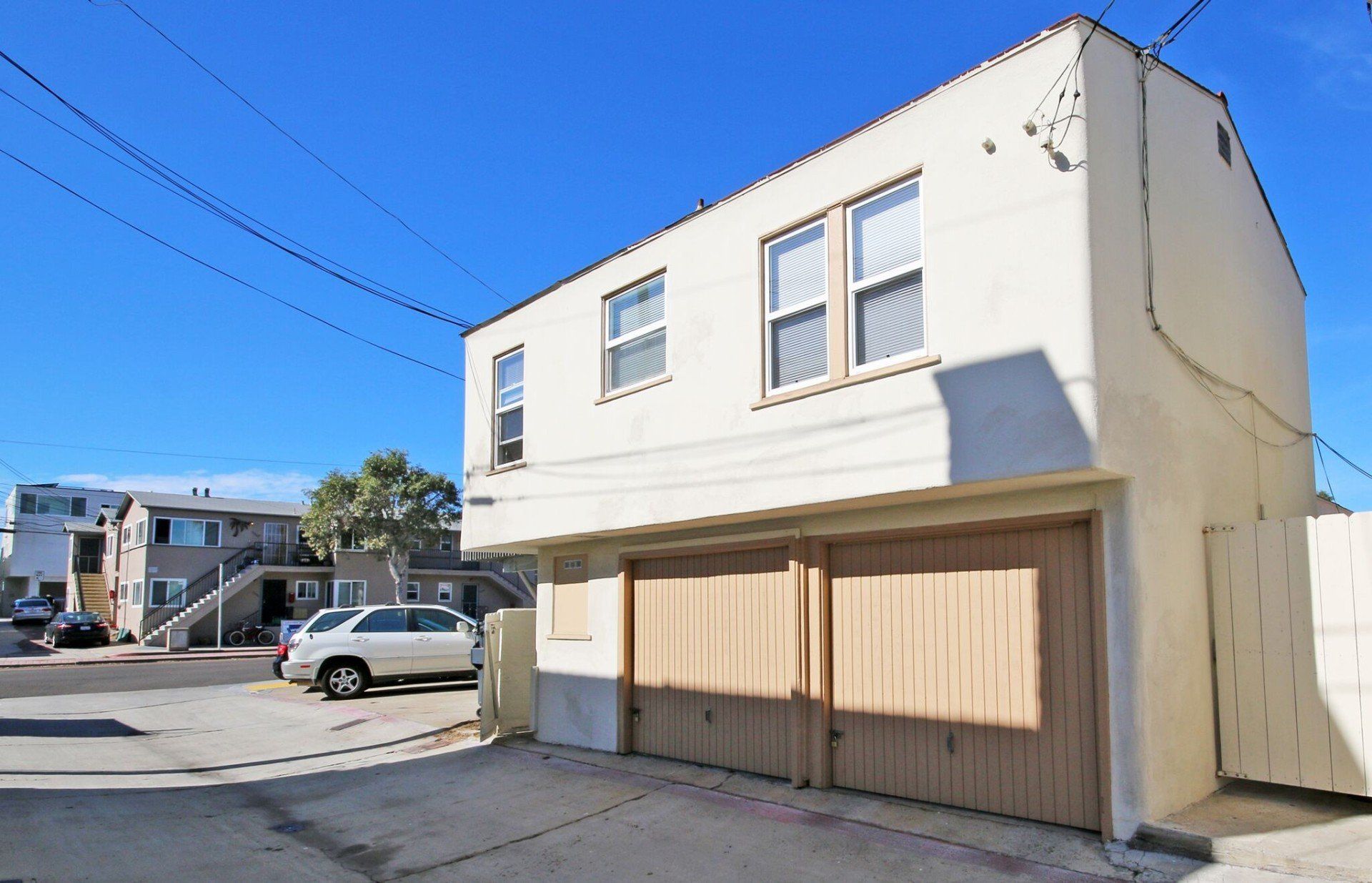 a white building with a wooden garage door and cars parked in front of it