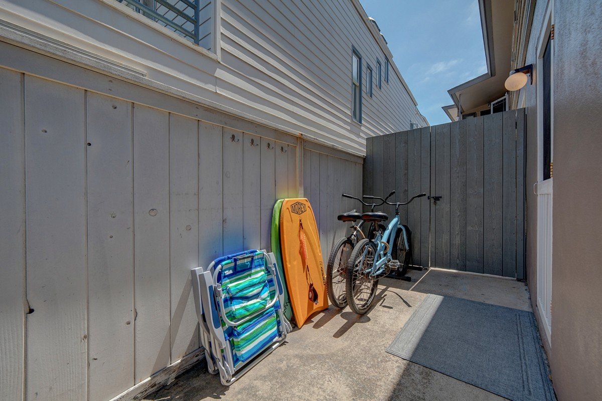 A bicycle is parked on the side of a building next to a fence.