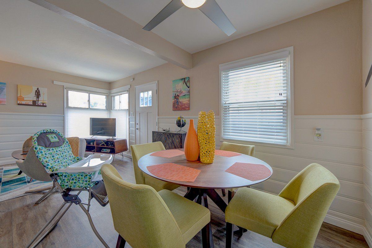 A living room with a table and chairs and a ceiling fan.