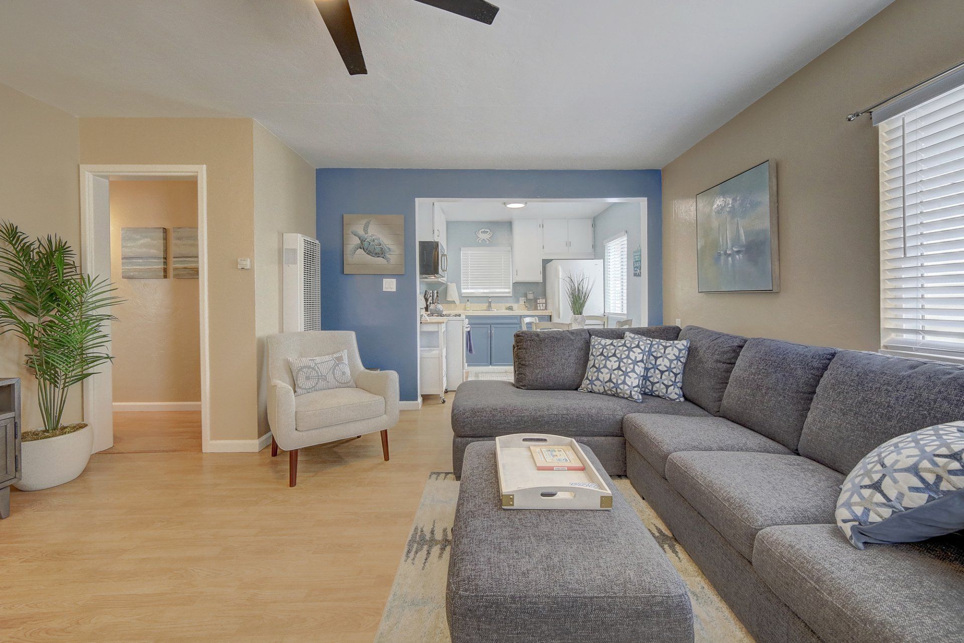 A living room with a large sectional couch and a ceiling fan