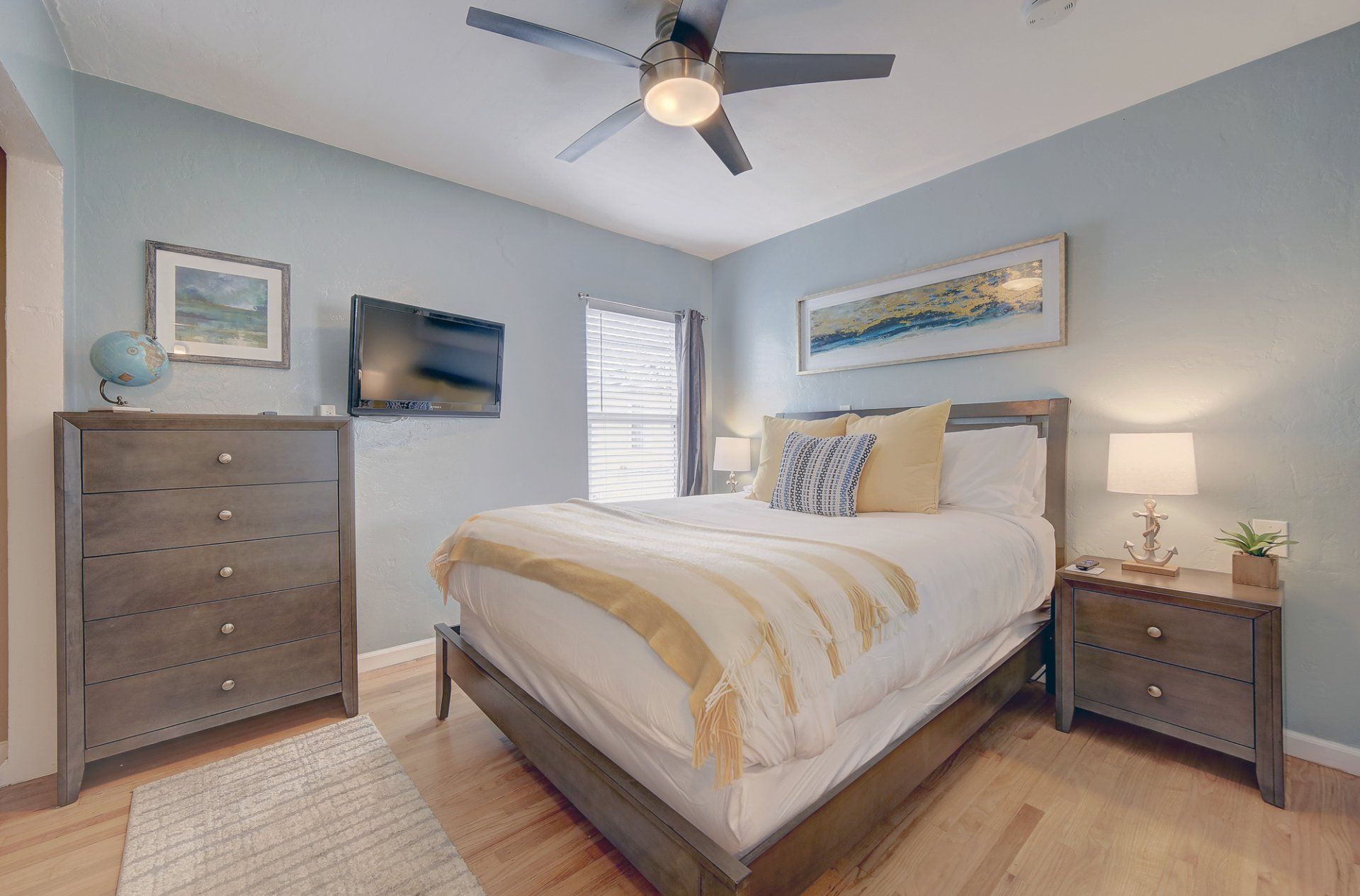 A bedroom with a king size bed , dresser , nightstand , television and ceiling fan.