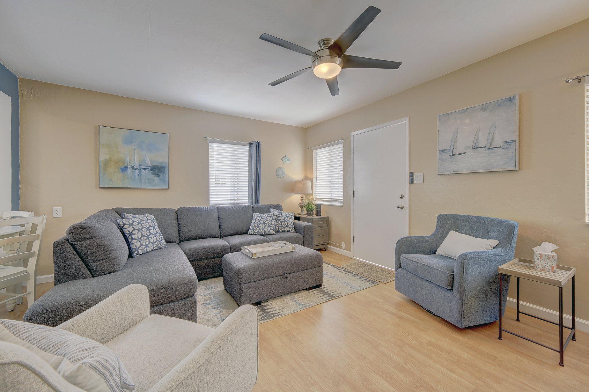 A living room with a couch , chair , ottoman and ceiling fan.