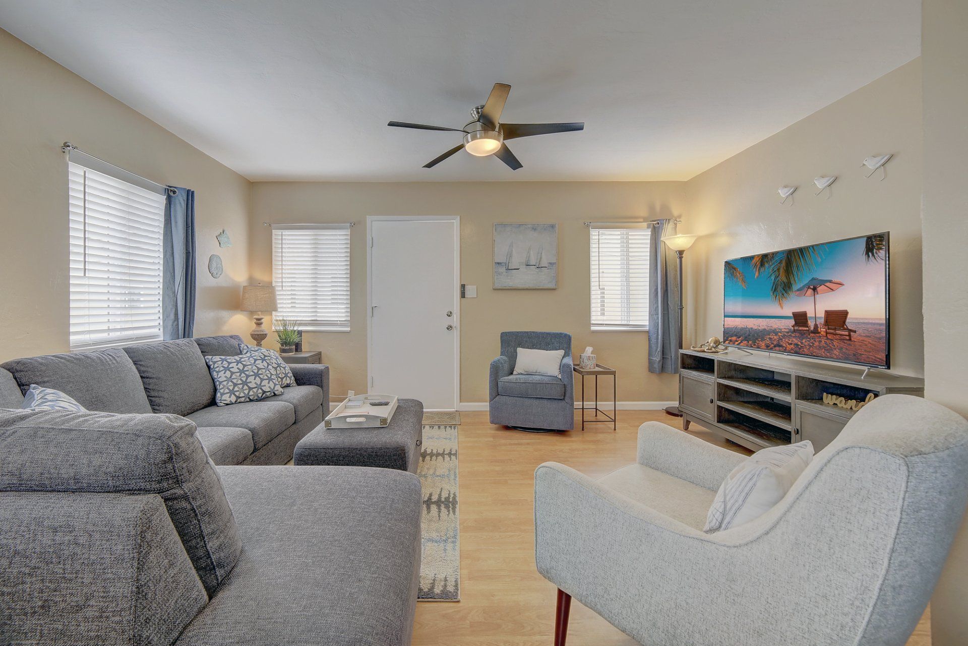 A living room with a couch , chair , television and ceiling fan.