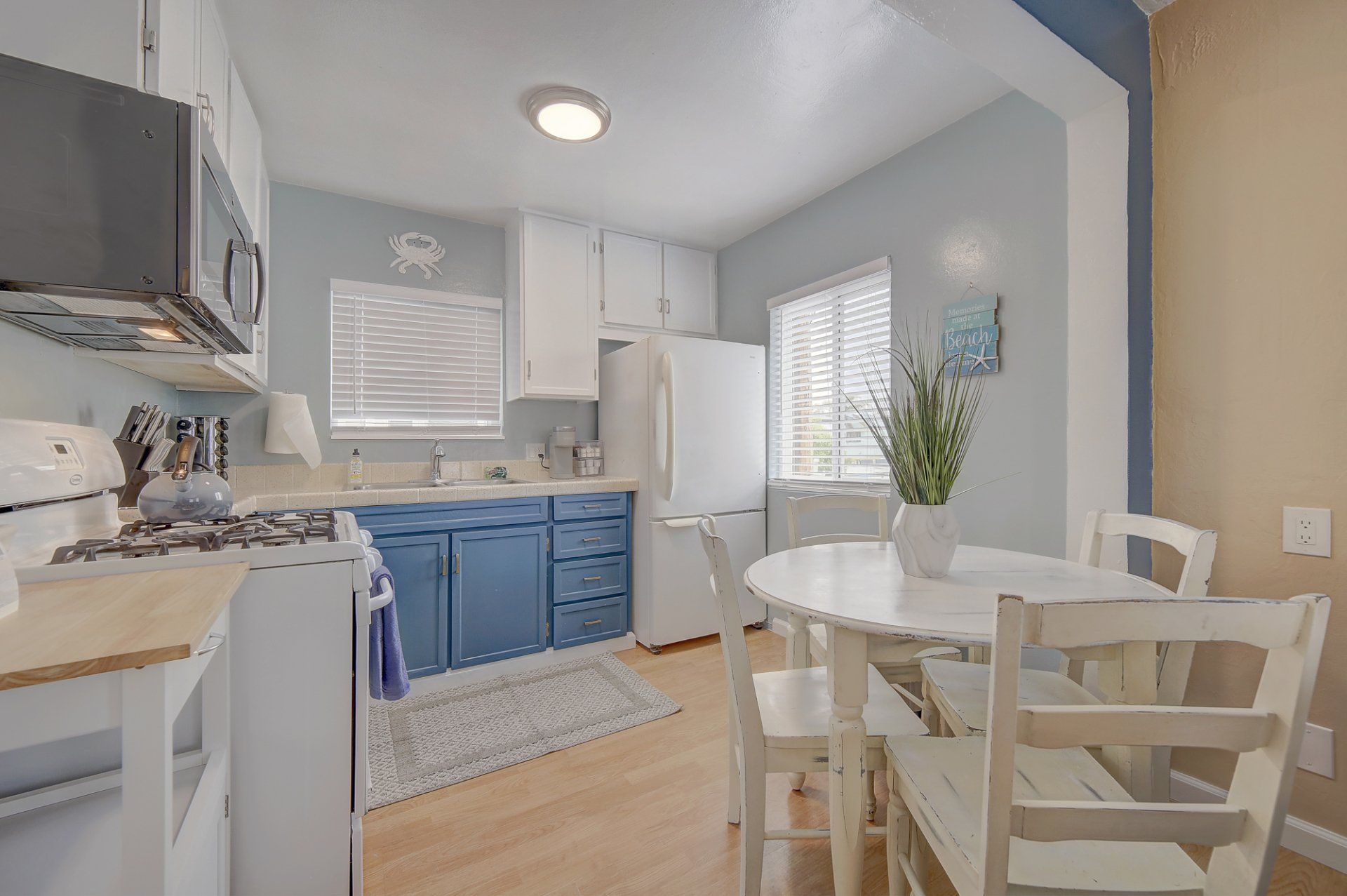 A kitchen with blue cabinets , white appliances , a table and chairs.