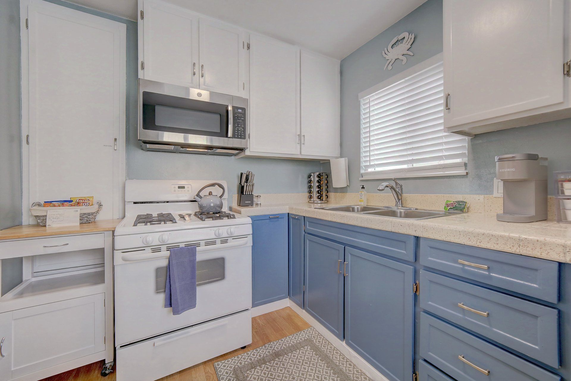 a kitchen with blue cabinets , a white stove , a microwave , and a sink .