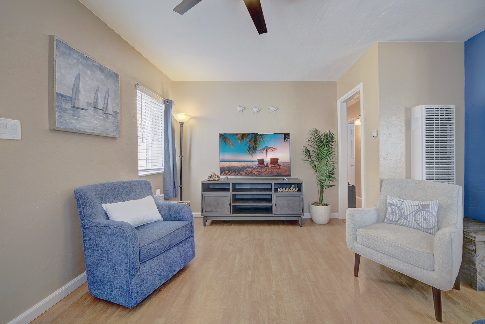 A living room with a couch , chair , television and ceiling fan.