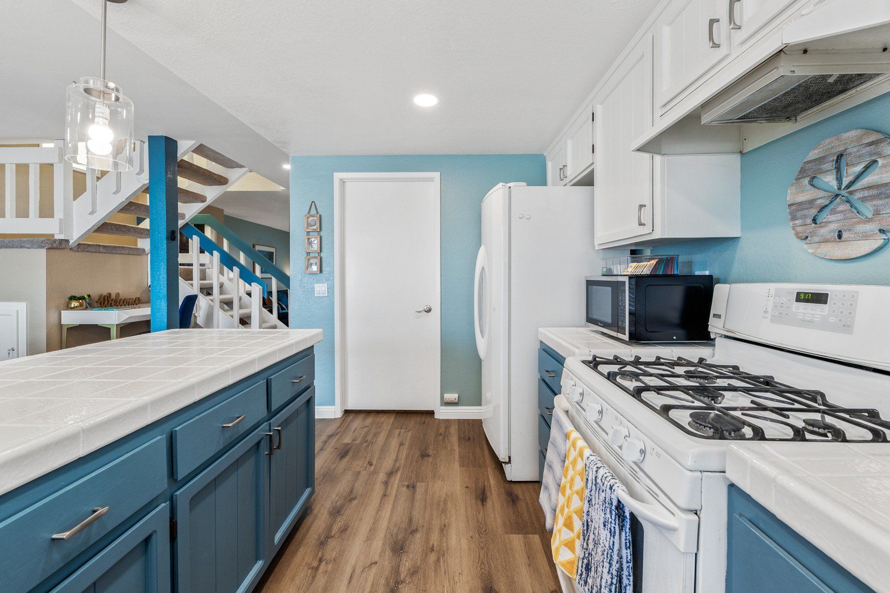 a kitchen with blue cabinets , a stove , a refrigerator , and a microwave .