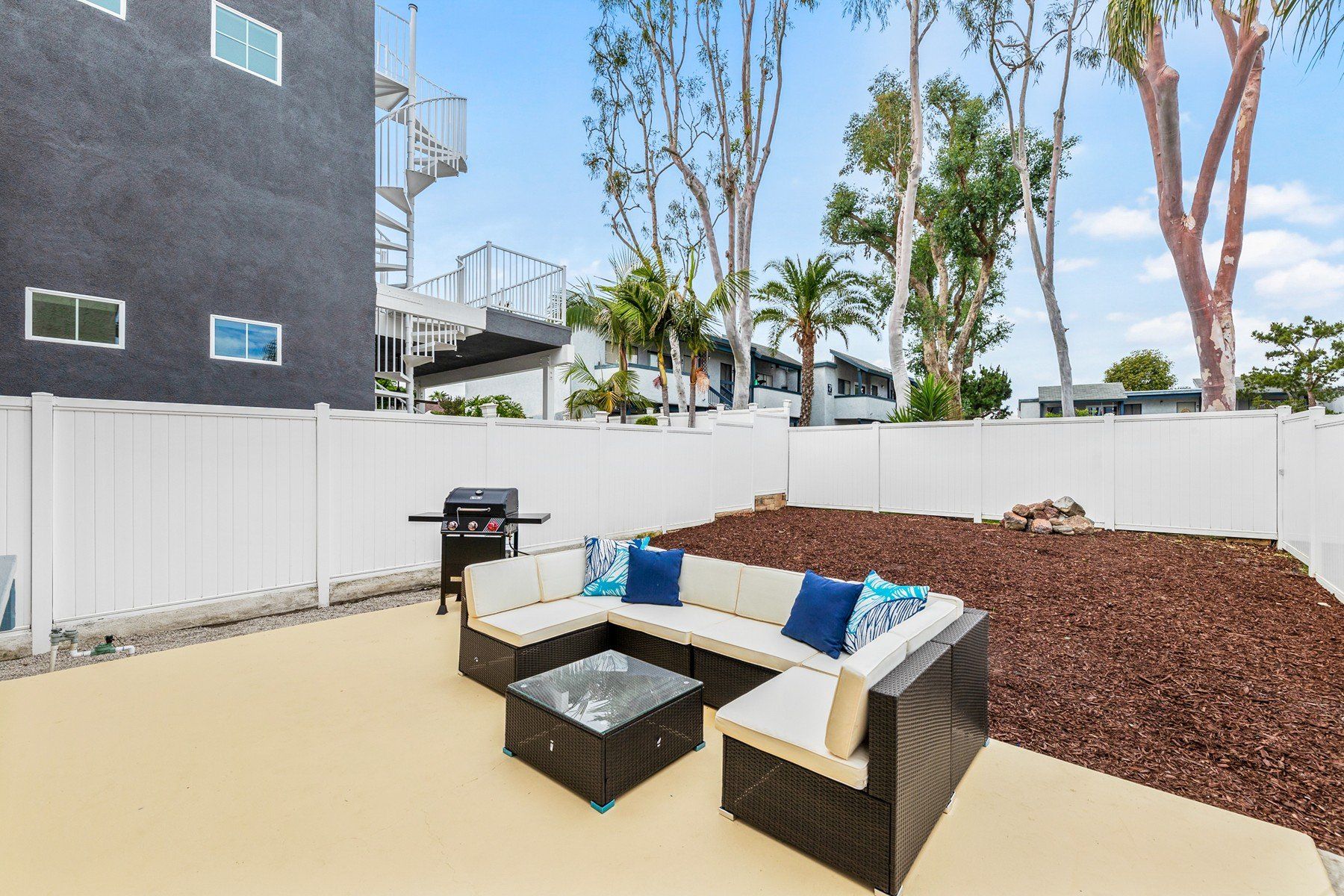 a backyard with a couch , table , and grill .