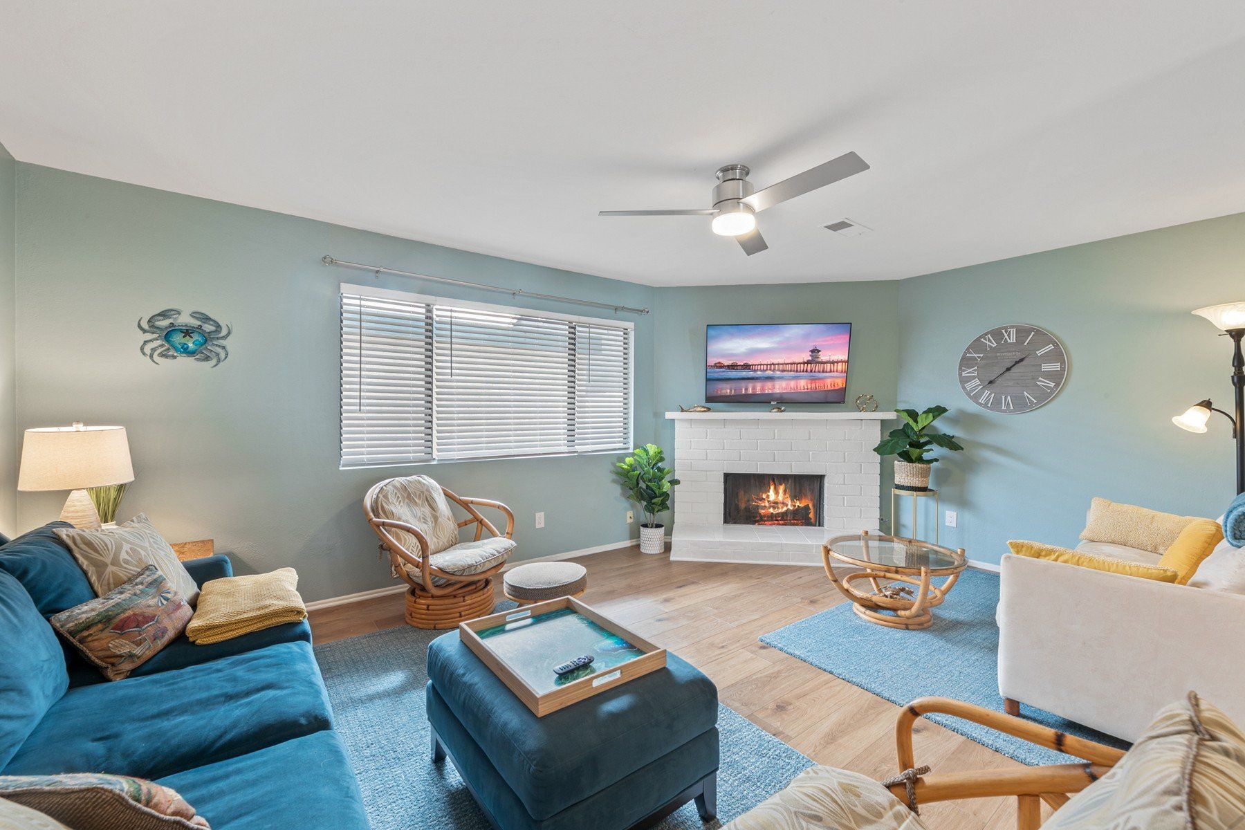 A living room with a blue couch , white chairs , a fireplace and a flat screen tv.