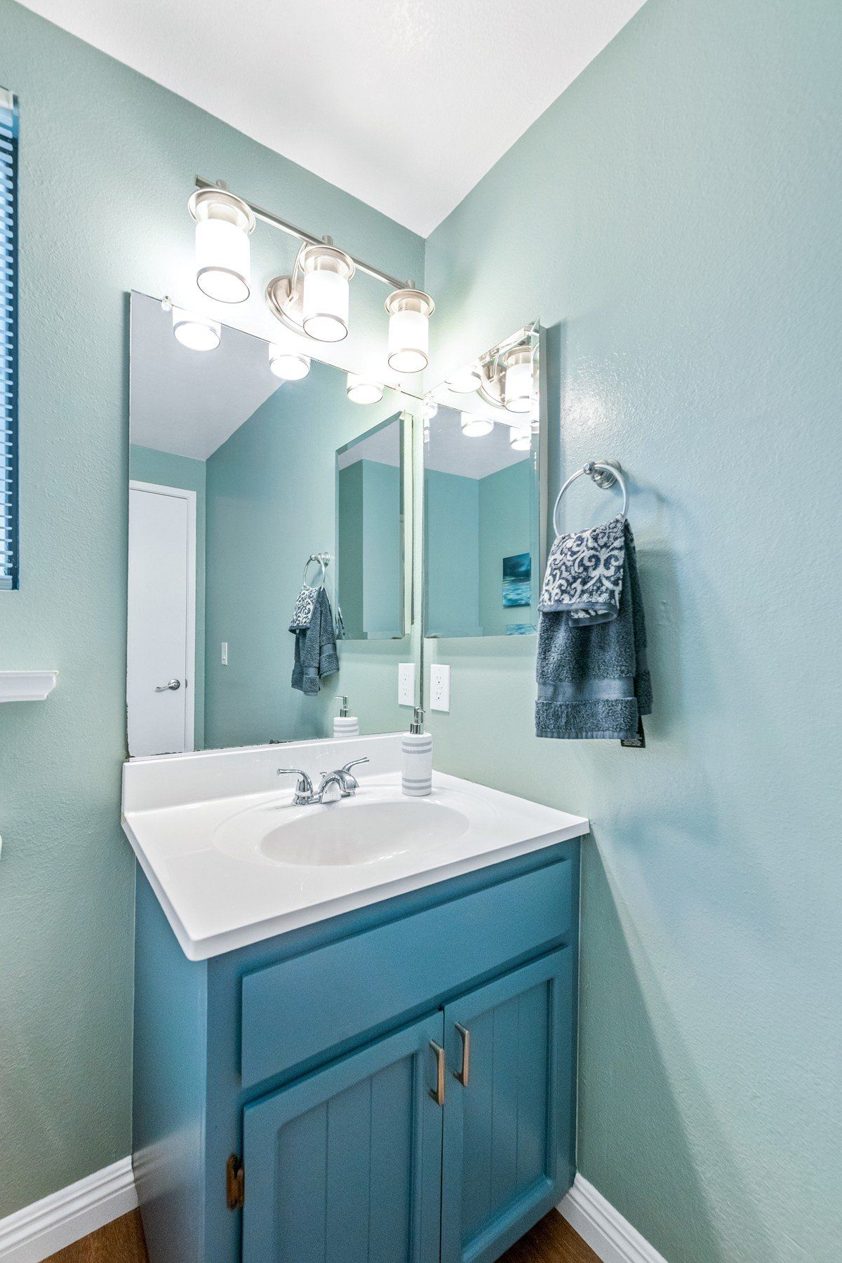 A bathroom with a sink , mirror and towel rack.