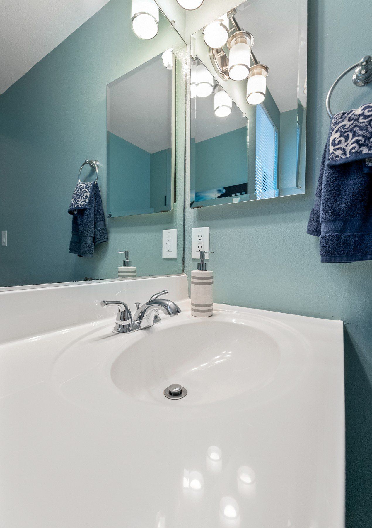 A bathroom sink with a mirror and towels hanging on the wall.