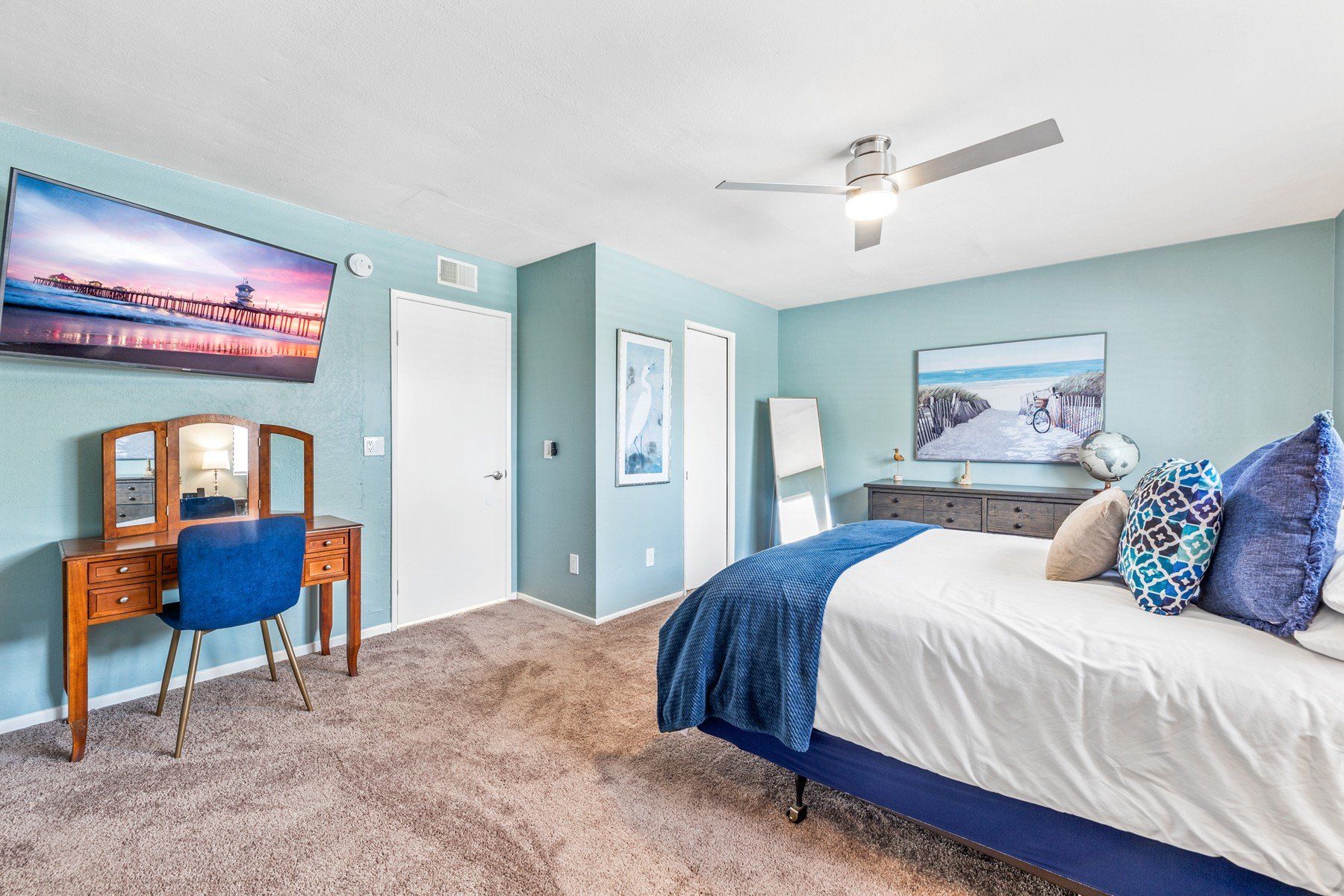 A bedroom with a bed , dresser , television and ceiling fan.