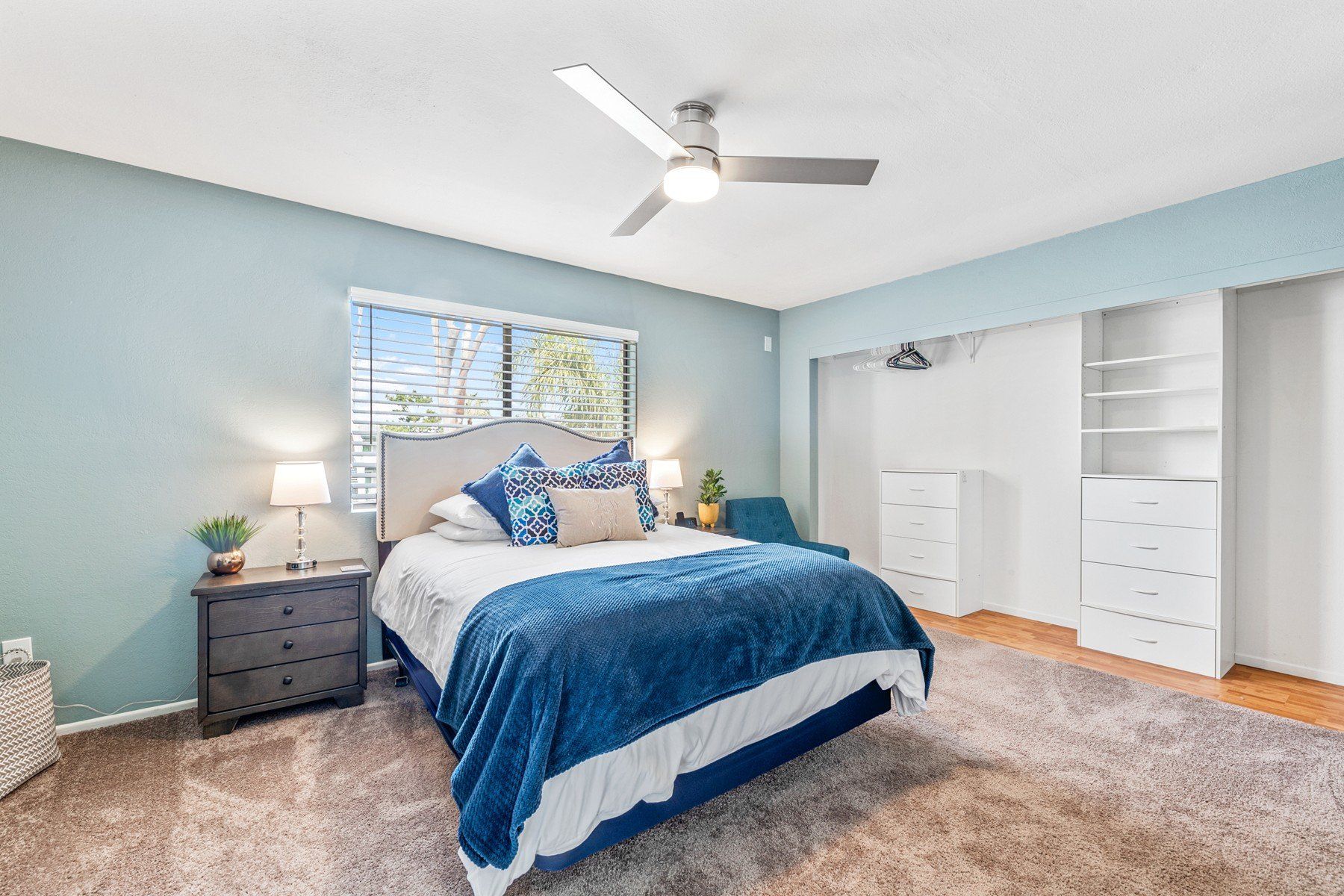 A bedroom with a bed , nightstand , dresser and ceiling fan.