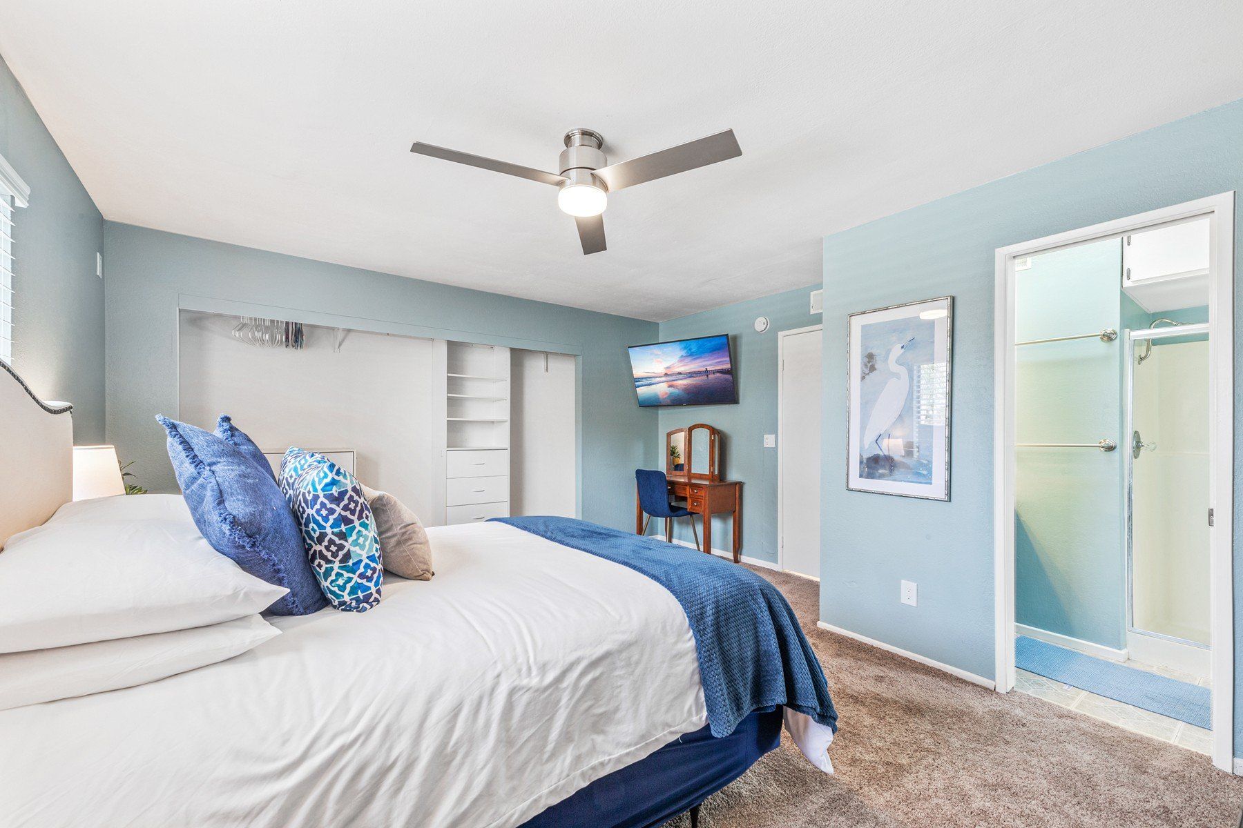 A bedroom with a king size bed and a ceiling fan.