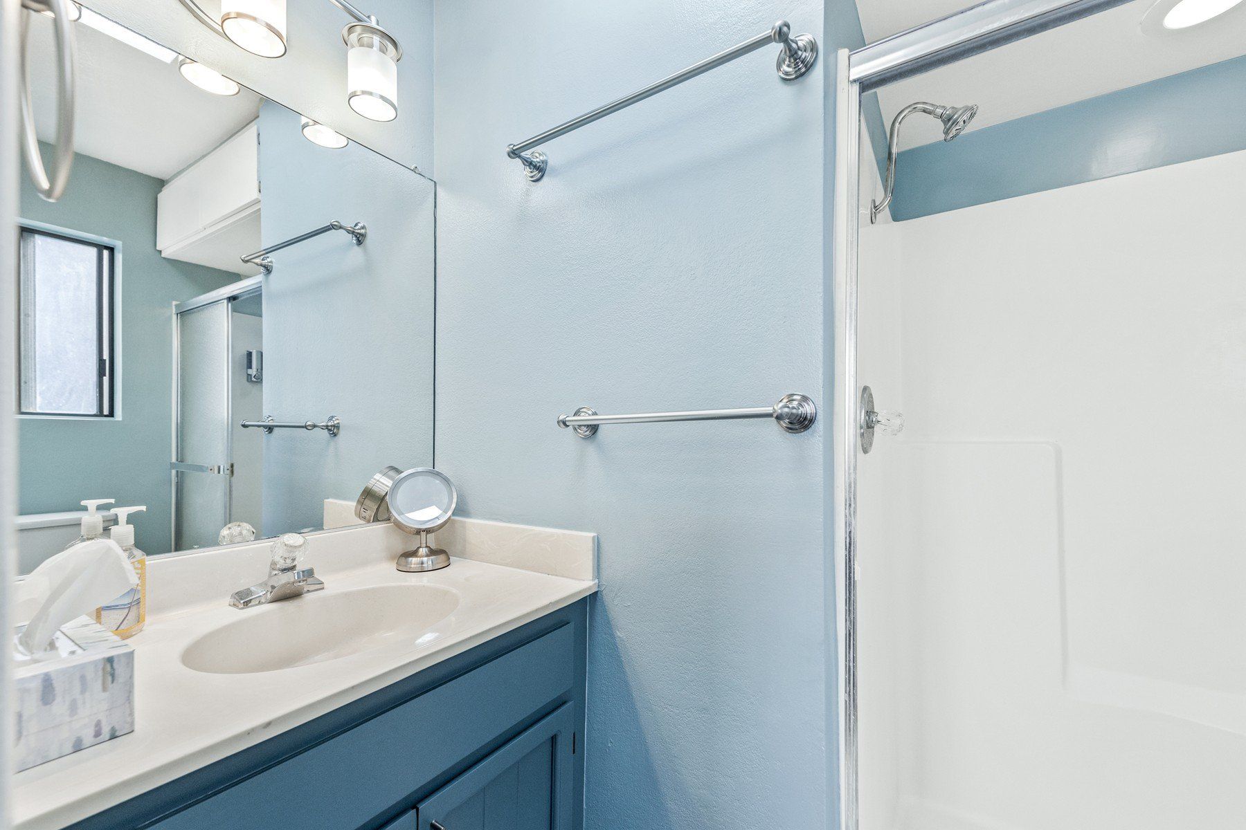 A bathroom with a sink , mirror and shower.