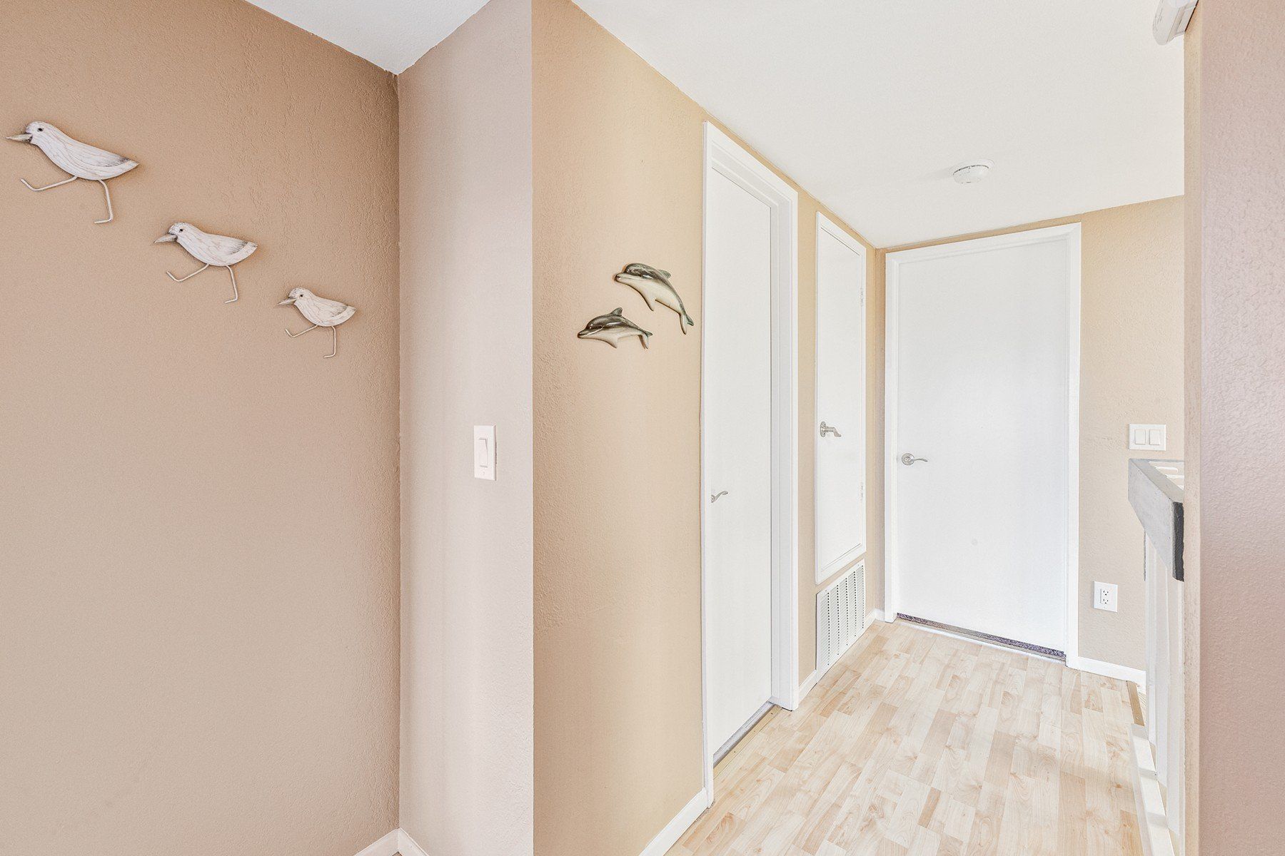 a hallway with birds on the wall and dolphins on the door .