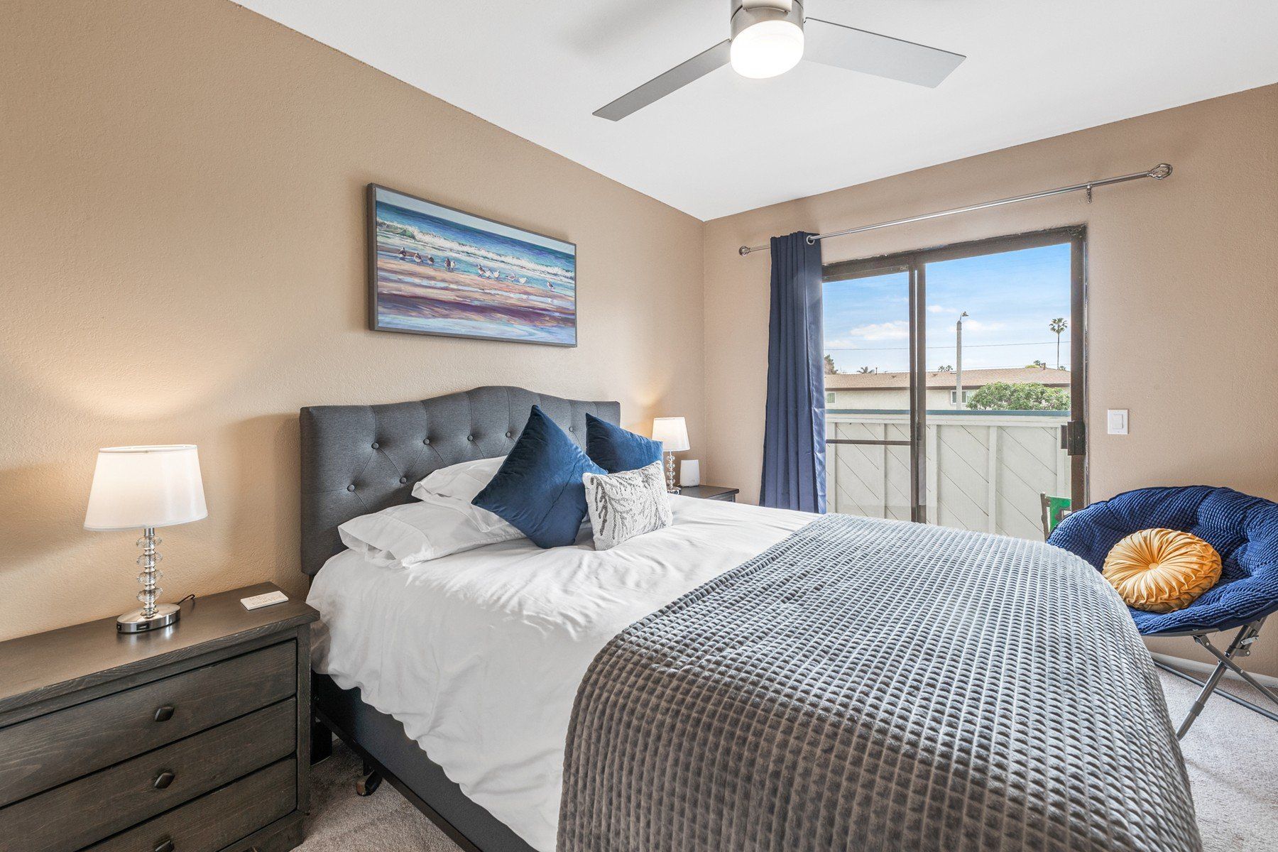 a bedroom with a bed , dresser , chair and ceiling fan .