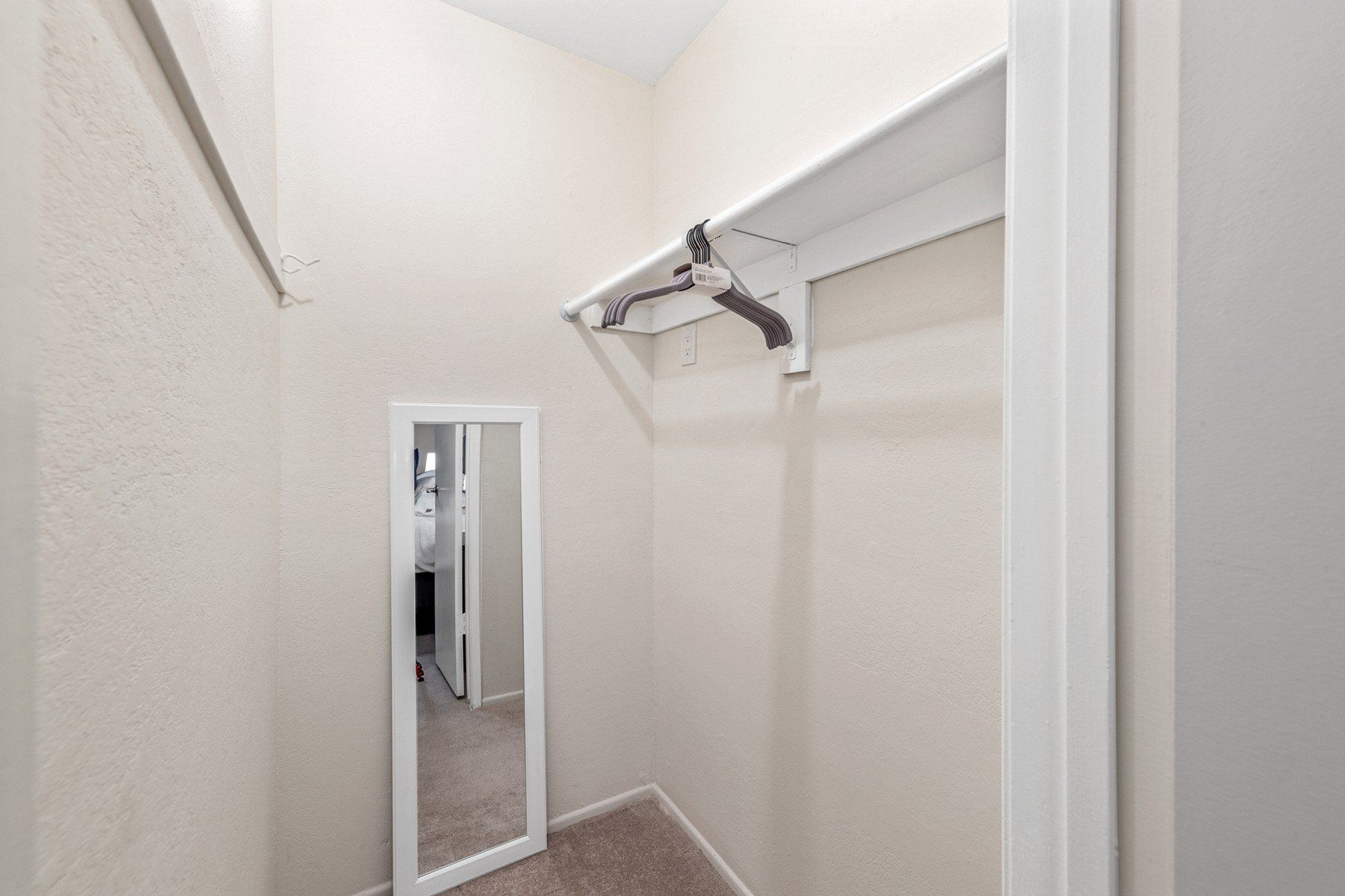 a walk in closet with a mirror and a shelf .